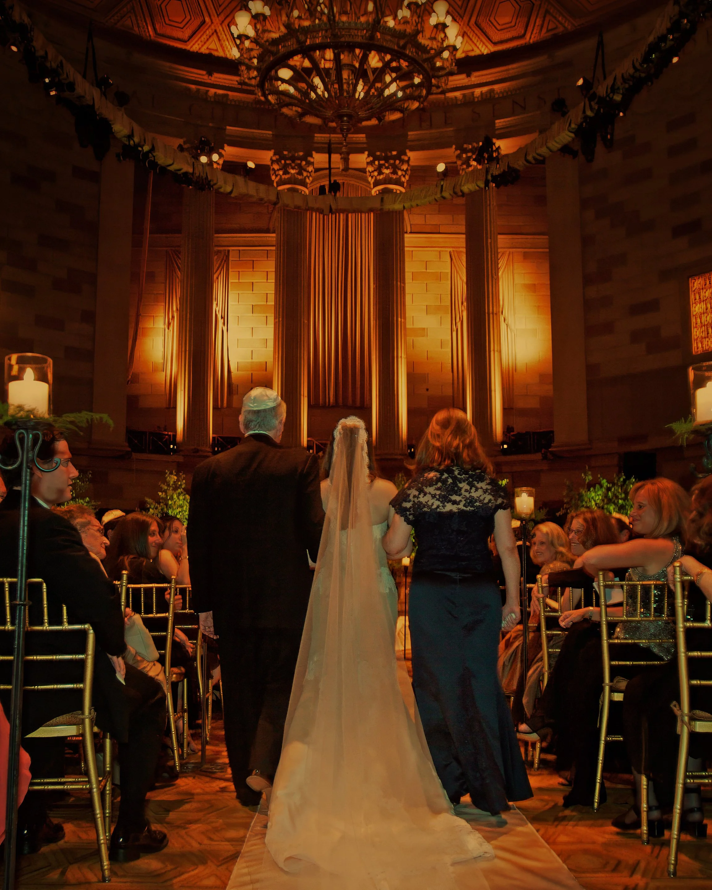 Bride escorted down the aisle by her parents during a Gotham Hall wedding ceremony in New York City.