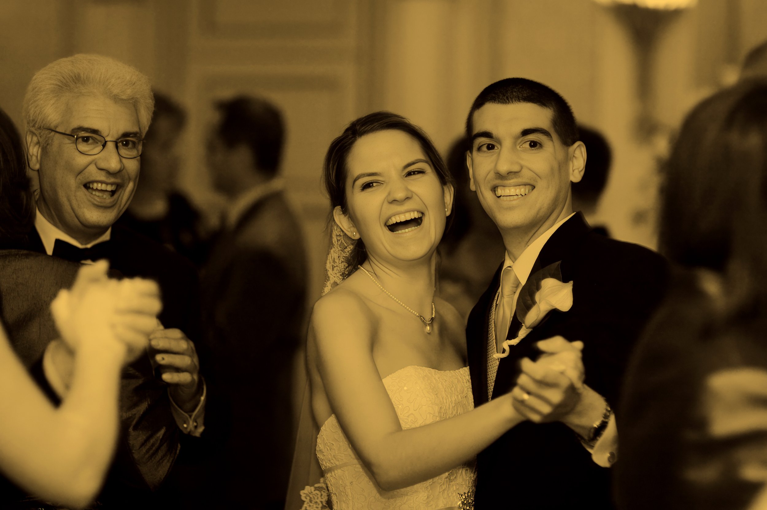Bride and groom enjoy their first dance with friends and family in a joyous fine art photograph