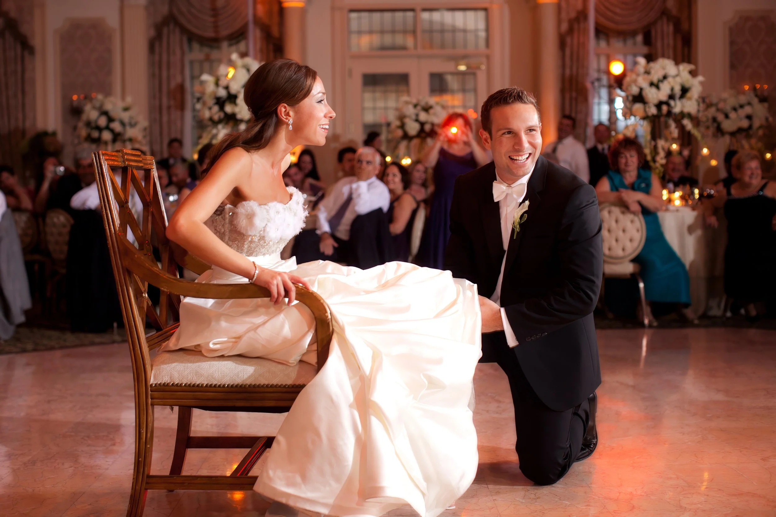 Groom playfully removes the bride’s garter during the reception at Pleasantdale Chateau.