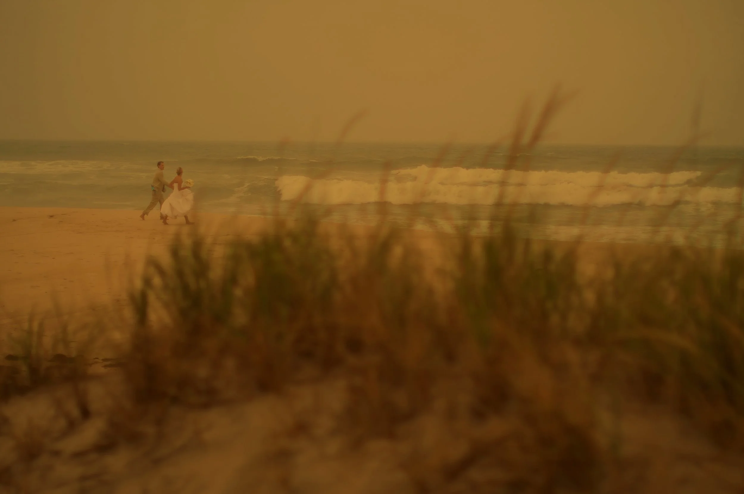 Bride and groom walk on the beach in The Hamptons on their wedding day