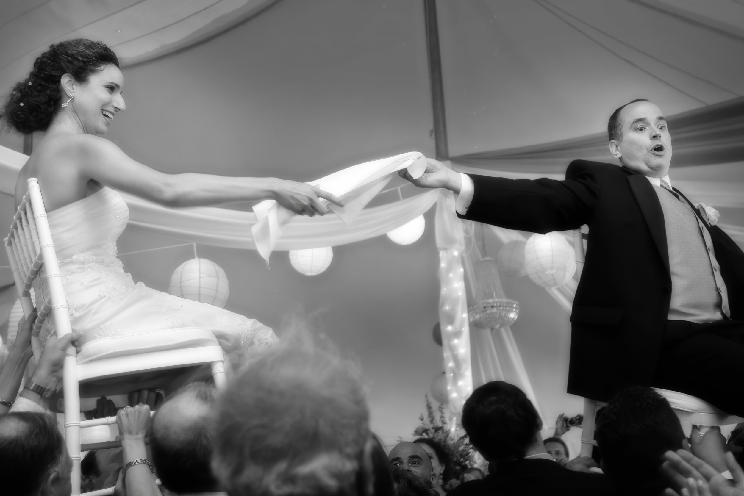 Bride and groom lifted on chairs during the hora dance under the tent at the Spa at Norwich