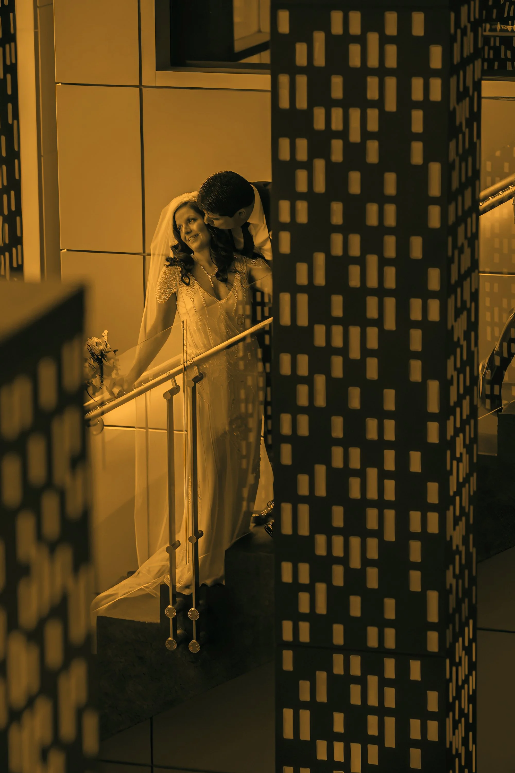Bride and groom kissing on the staircase inside W Hoboken during their wedding day.