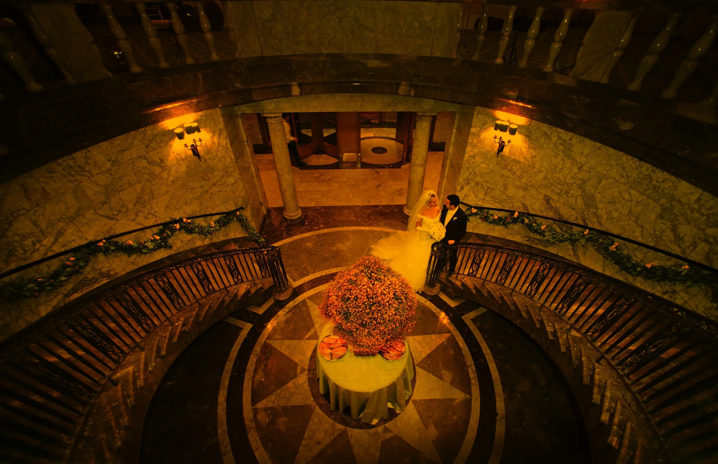 Bride and groom sharing a romantic moment at the base of the grand staircase at 48 Wall Street in New York City.