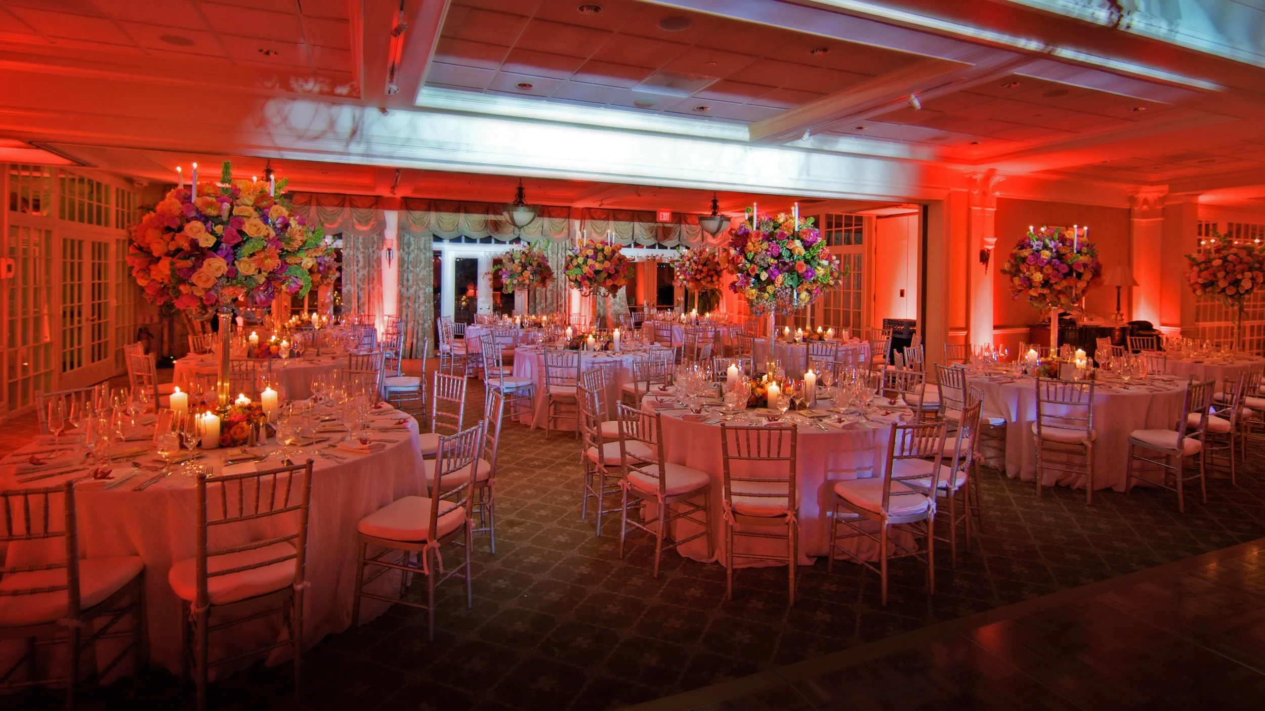 Ballroom decorated for a wedding reception at Preakness Hills Country Club with tall floral arrangements.