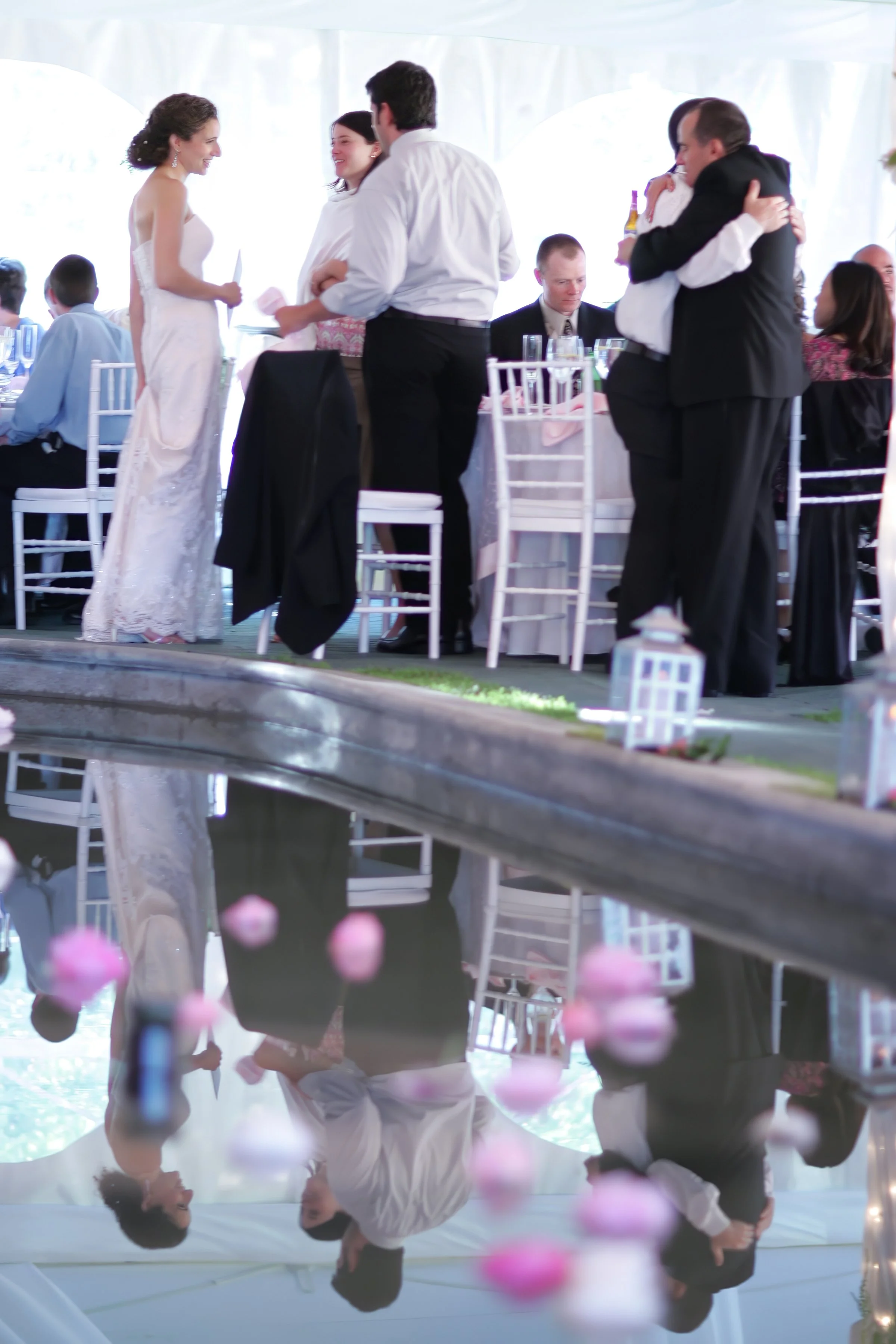 Bride and groom greeting guests beside reflecting pool tented reception at Spa at Norwich Inn