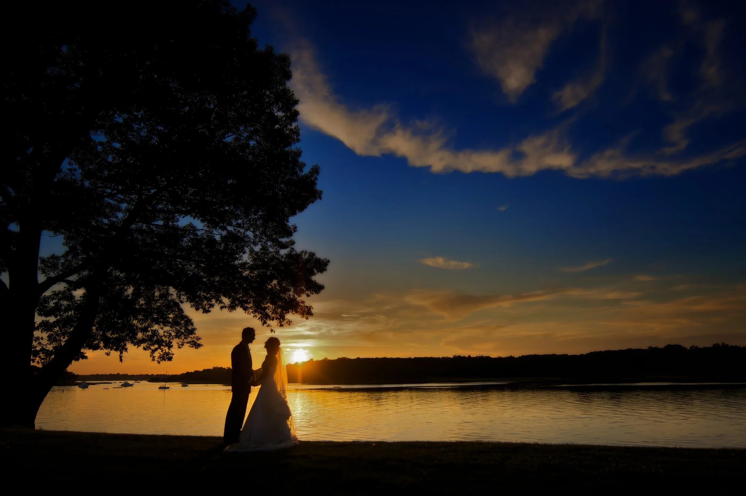 Bride and groom holding hands in a romantic sunset portrait on Milton Harbor at their Wainwright House wedding reception.