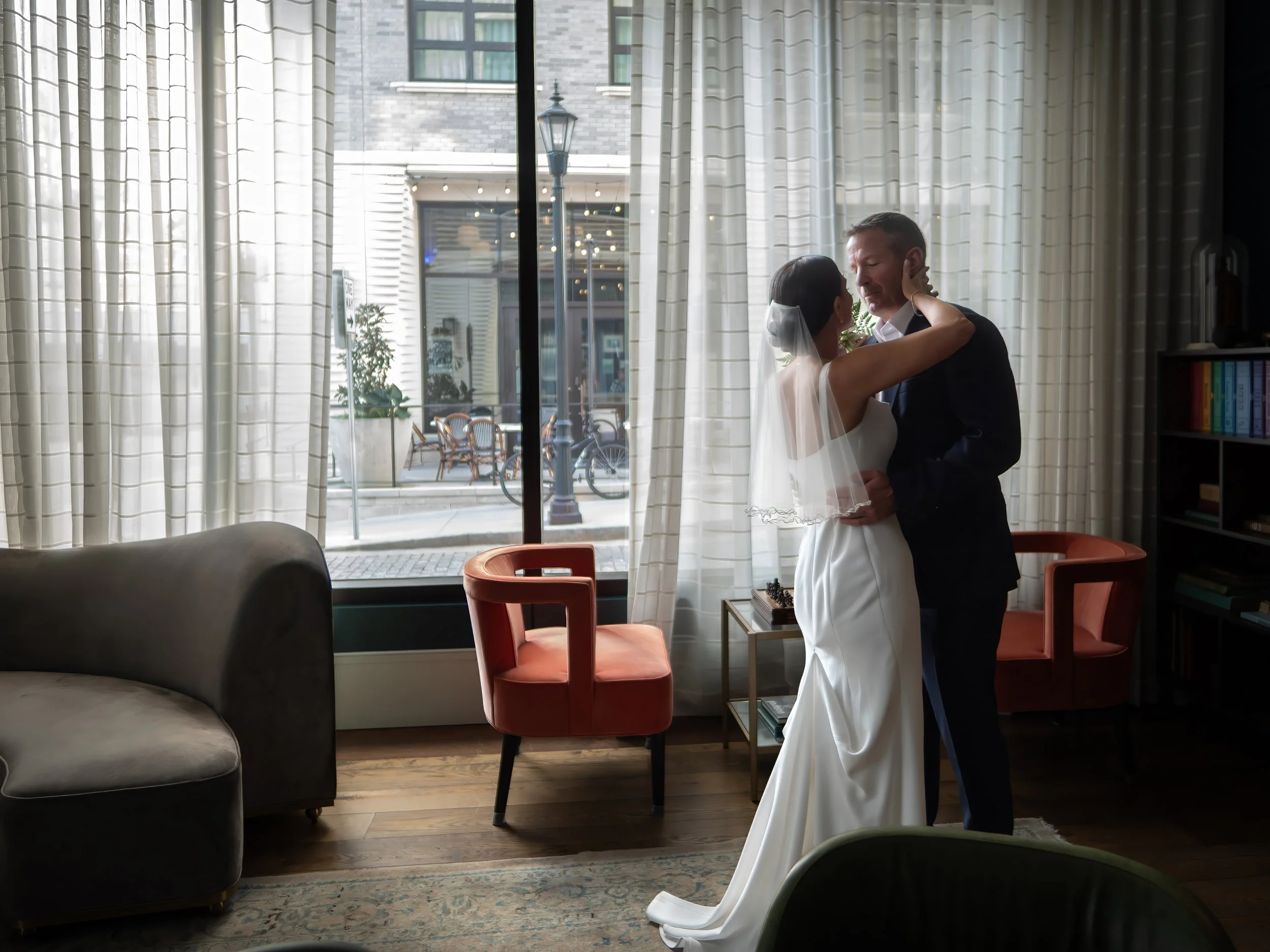 Bride and groom embracing beside the windows inside the Perry Lane Hotel library