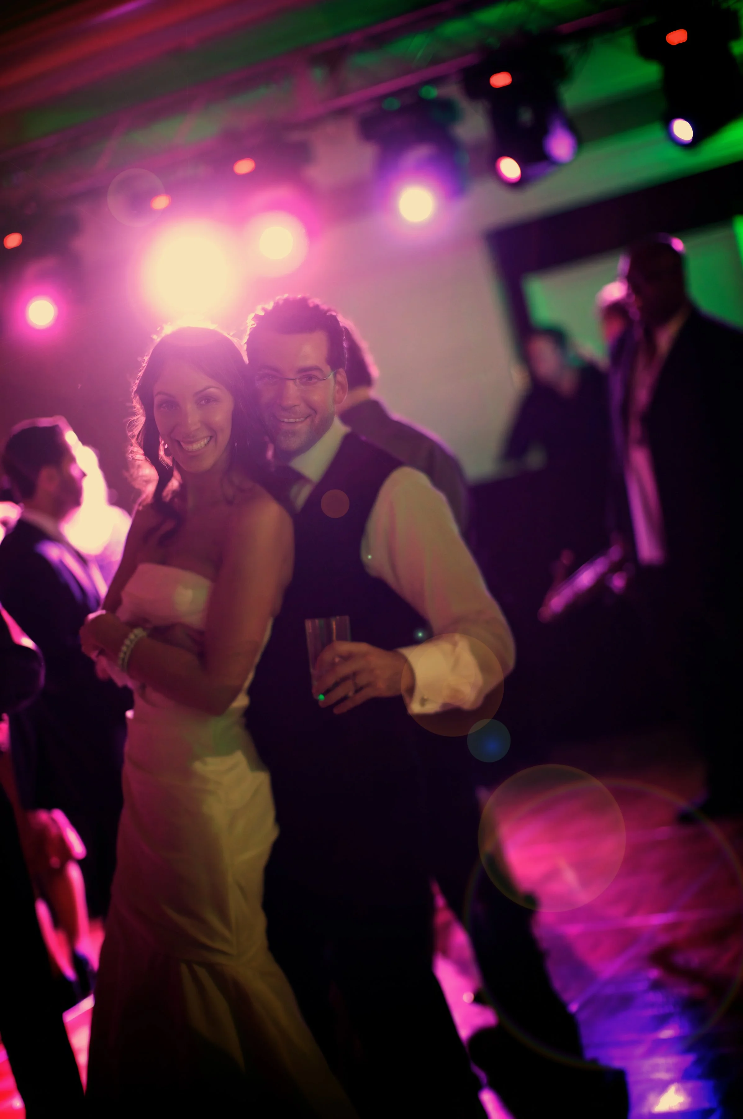 Bride and groom look to the camera with joyful expressions as they dance at their wedding reception.