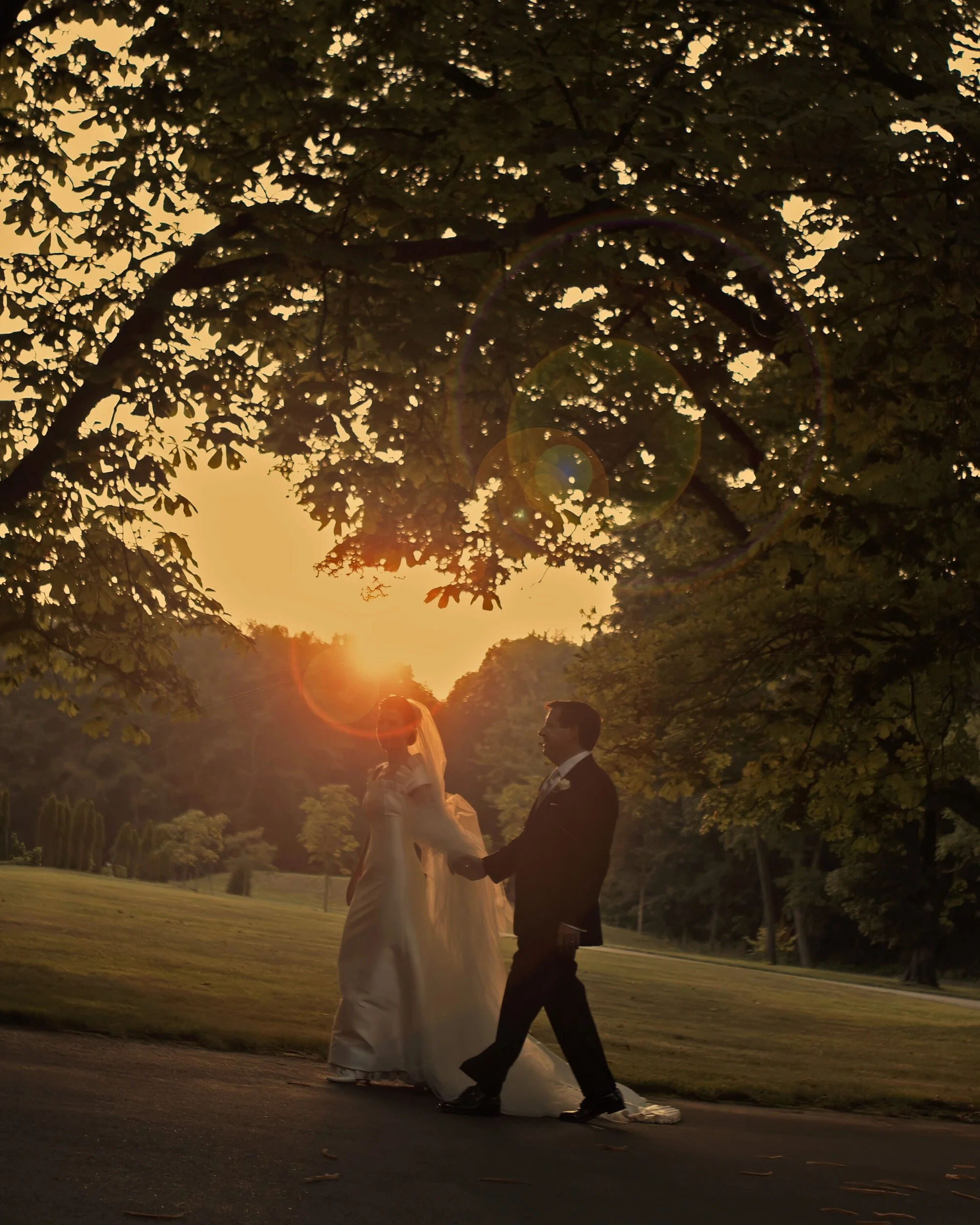 Bride and groom walking down the driveway toward Saint Clements Castle in late afternoon sunlight