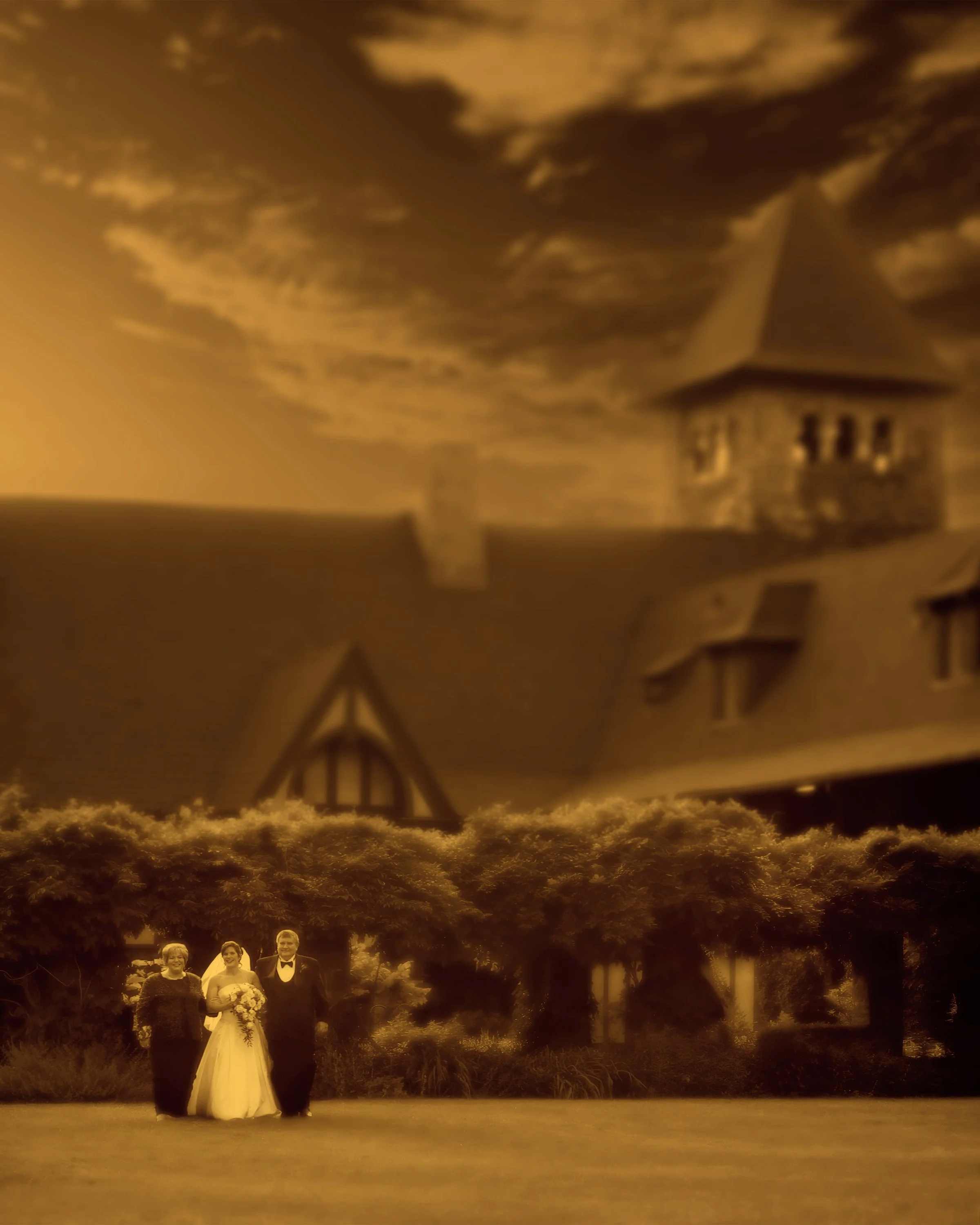 Parents walking the bride toward her ceremony on the lawn with Saint Clements Castle in the background