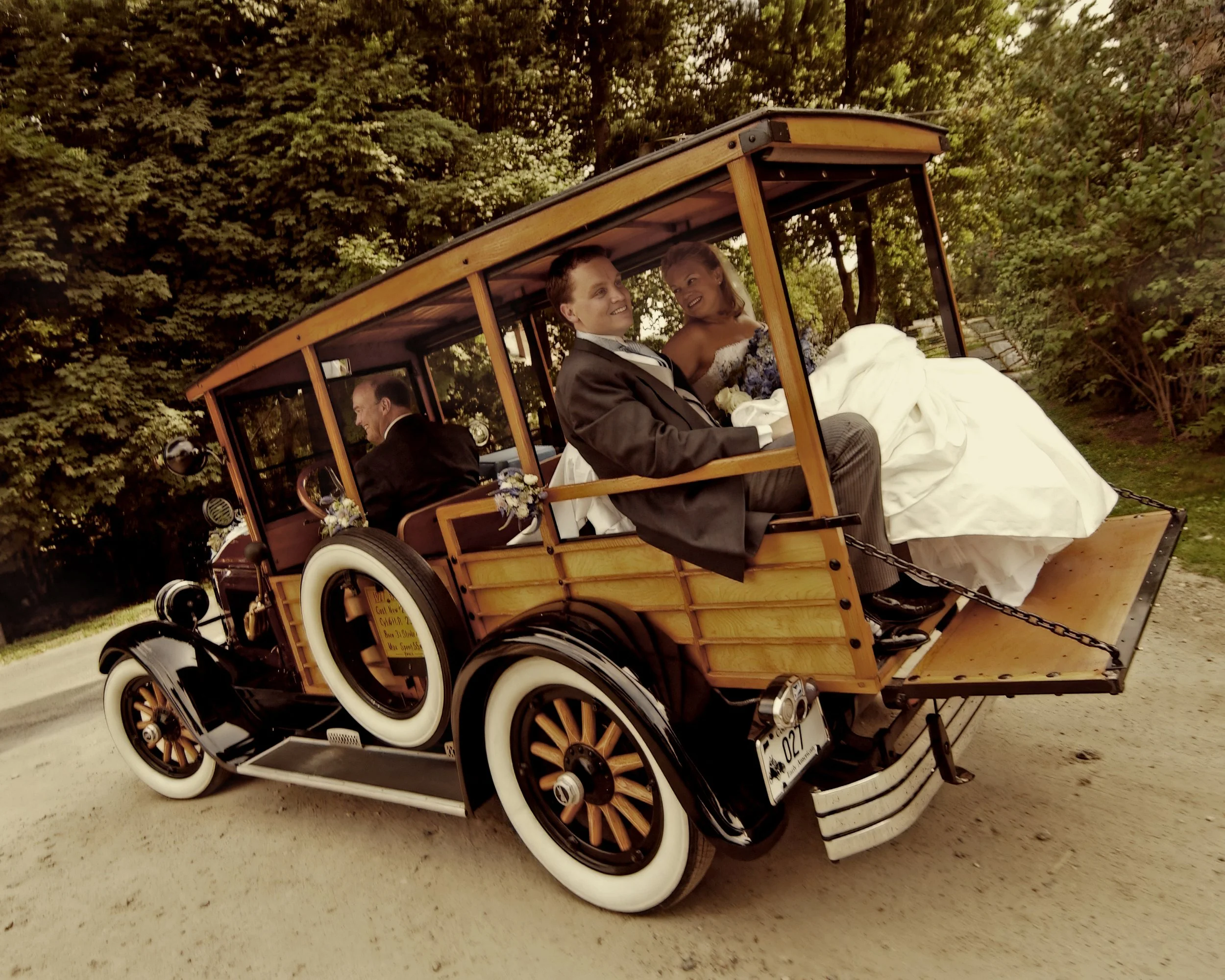Father of the bride driving a vintage car with bride and groom seated in the back in Litchfield County.