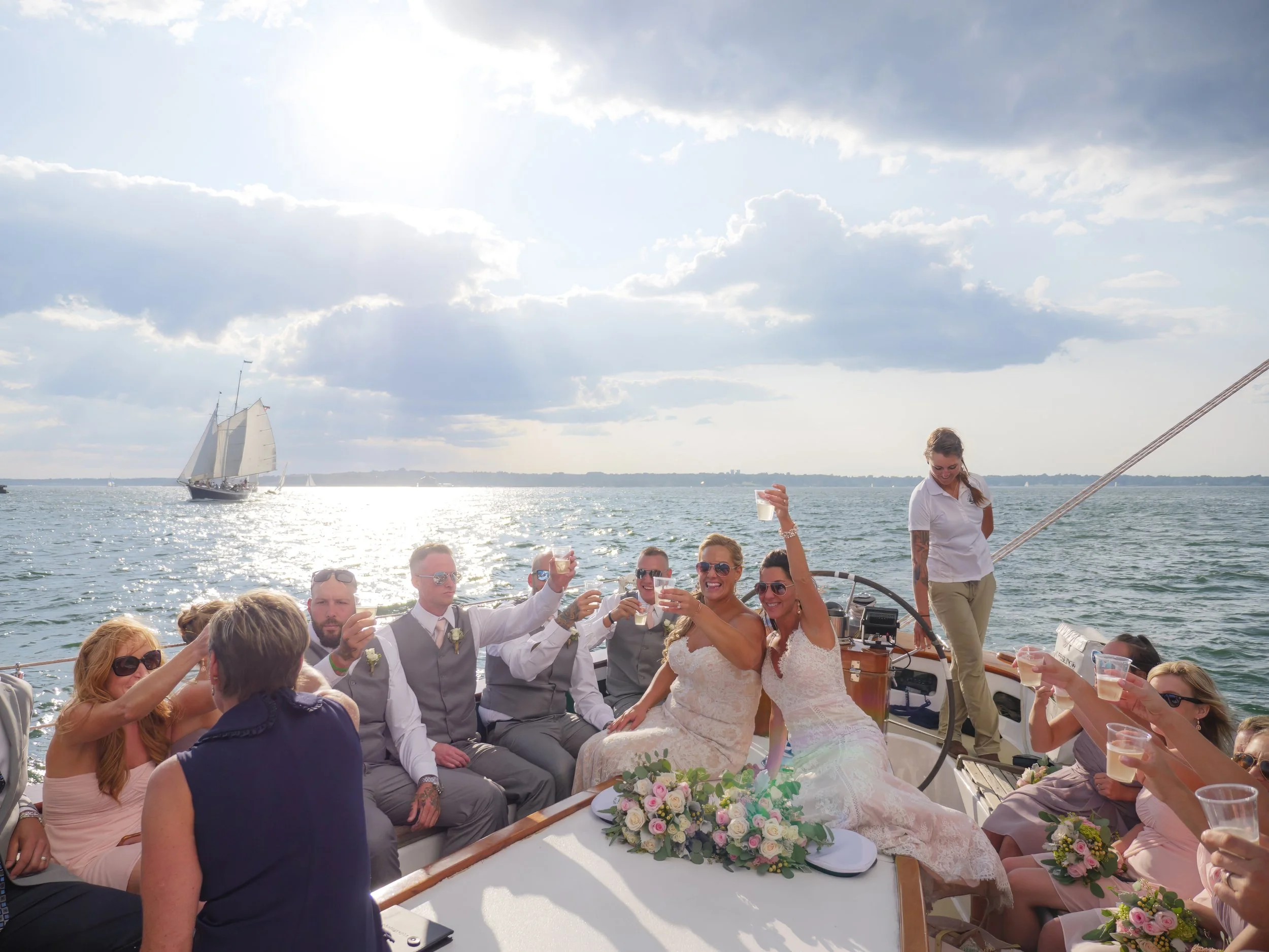 Wedding party toasts under sail aboard a 100 foot schooner on Narragansett Bay.
