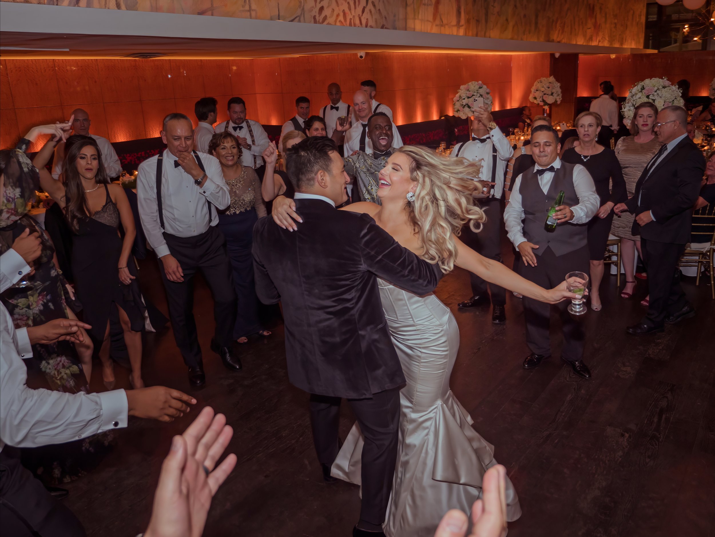 Bride and groom dance joyfully surrounded by friends and family on the dance floor at Bryant Park Grill in New York City.