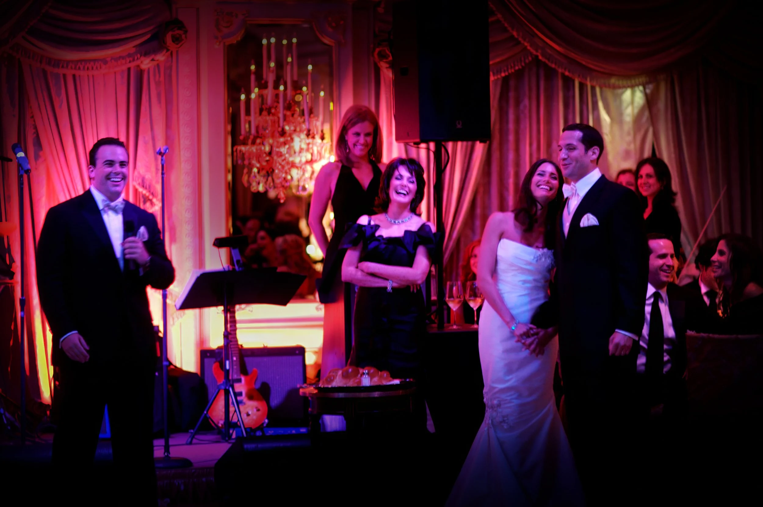 Wedding toast to the bride and groom at The St. Regis New York ballroom with colorful ambient lighting and emotional reactions from guests.