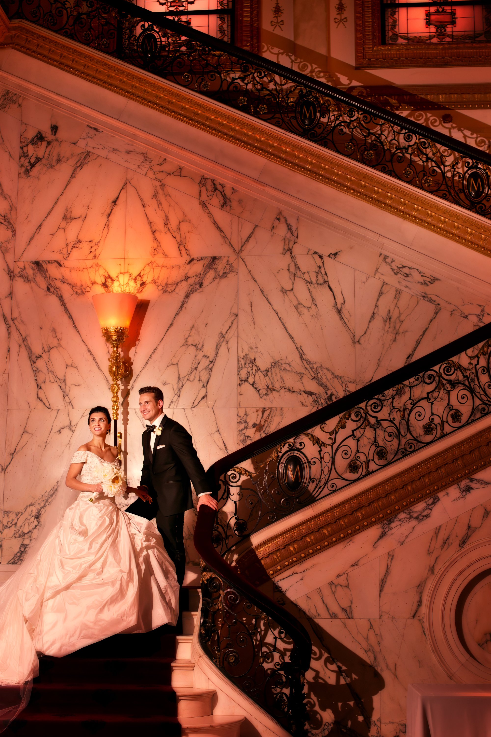 Bride and groom pause for legacy portrait on grand staircase at Metropolitan Club luxury wedding NYC