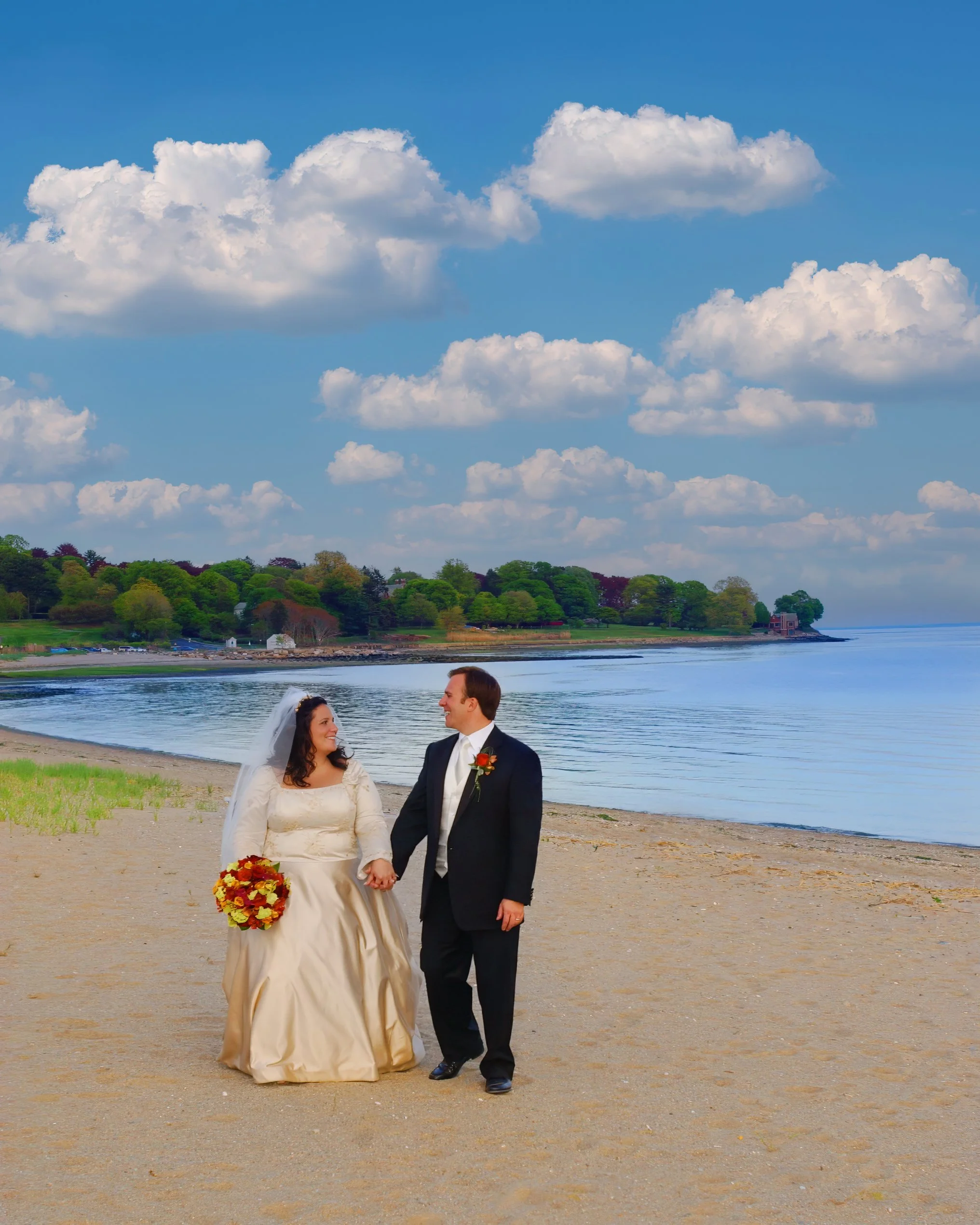 Bride and groom walking hand in hand along the beach in Southport, Connecticut.