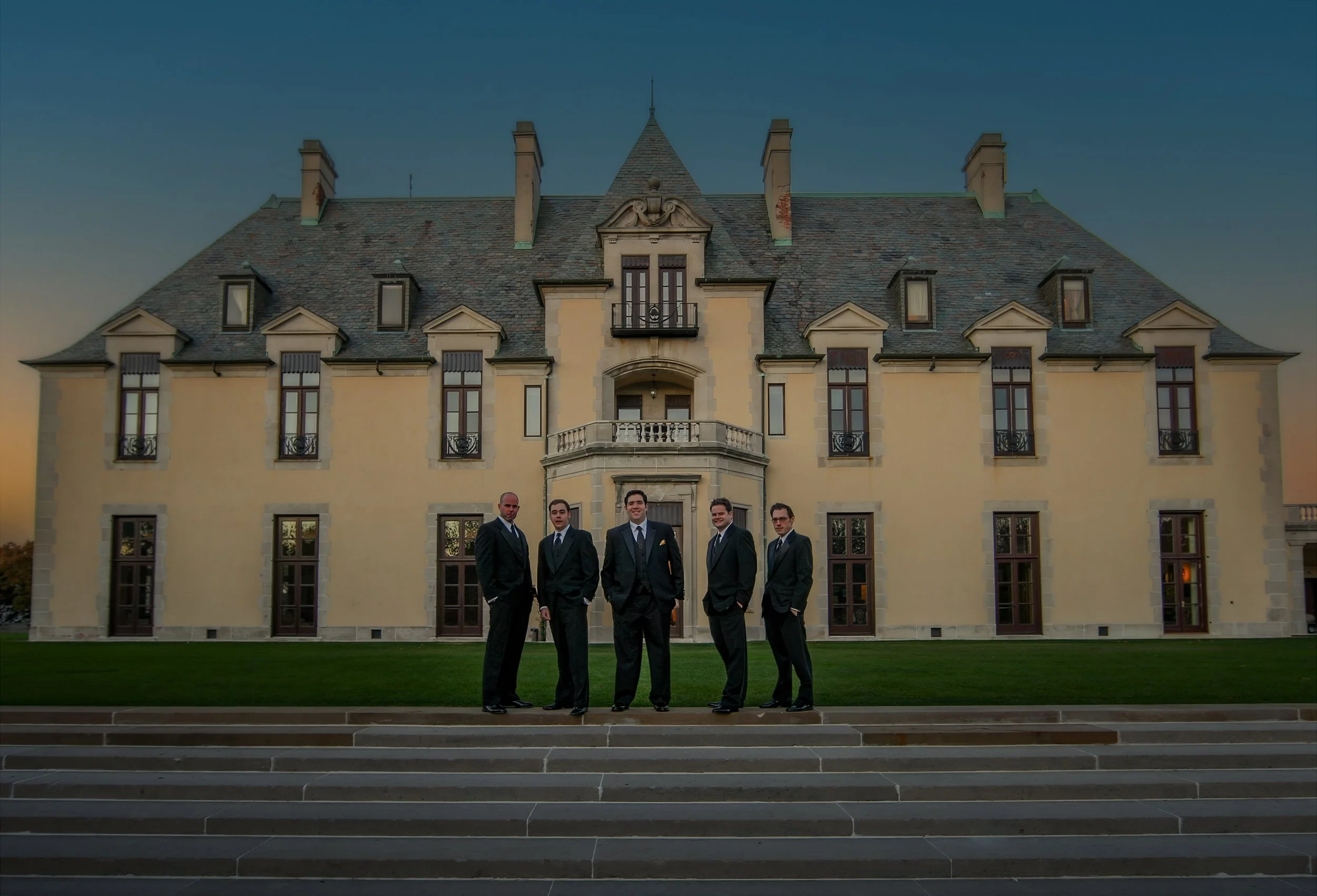 Groomsmen standing in front of the grand historic facade of Oheka Castle during a New York estate wedding.