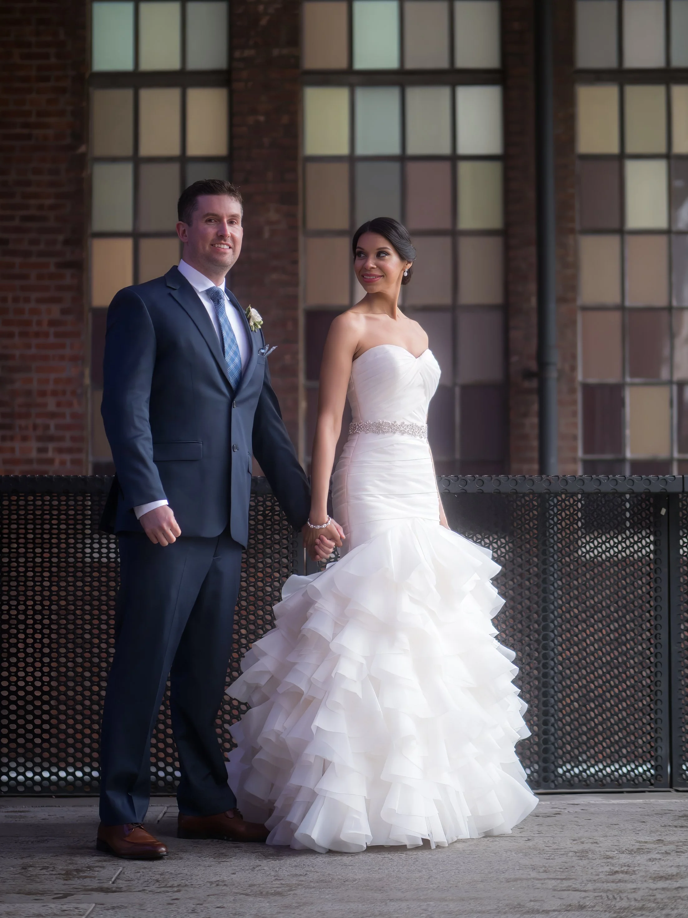 Bride and groom pause for a portrait surrounded by High Line architecture during a rainy NYC wedding photoshoot.