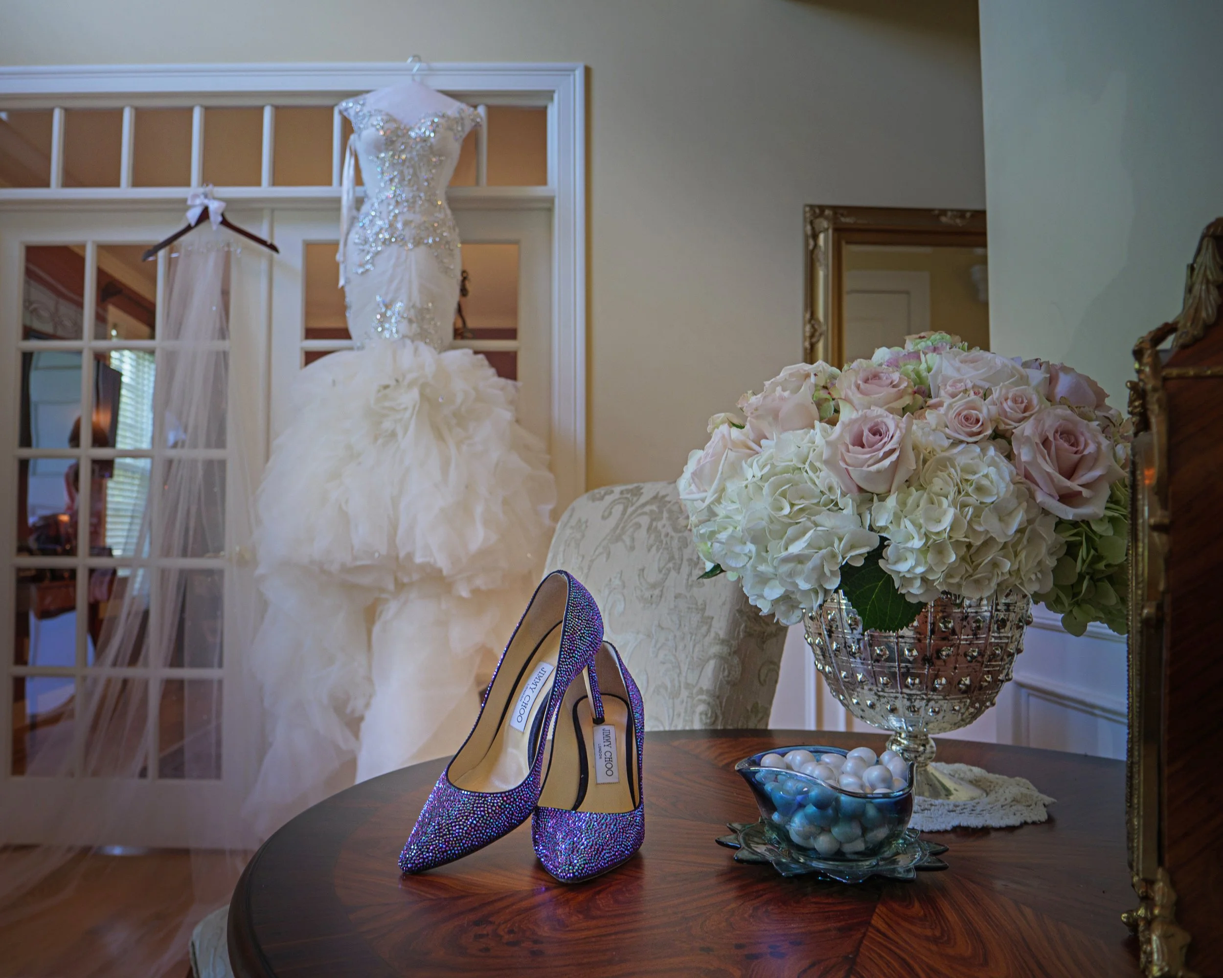 Bride’s Jimmy Choo shoes framed in the foyer of her family home with her wedding dress softly visible in the background during morning preparations
