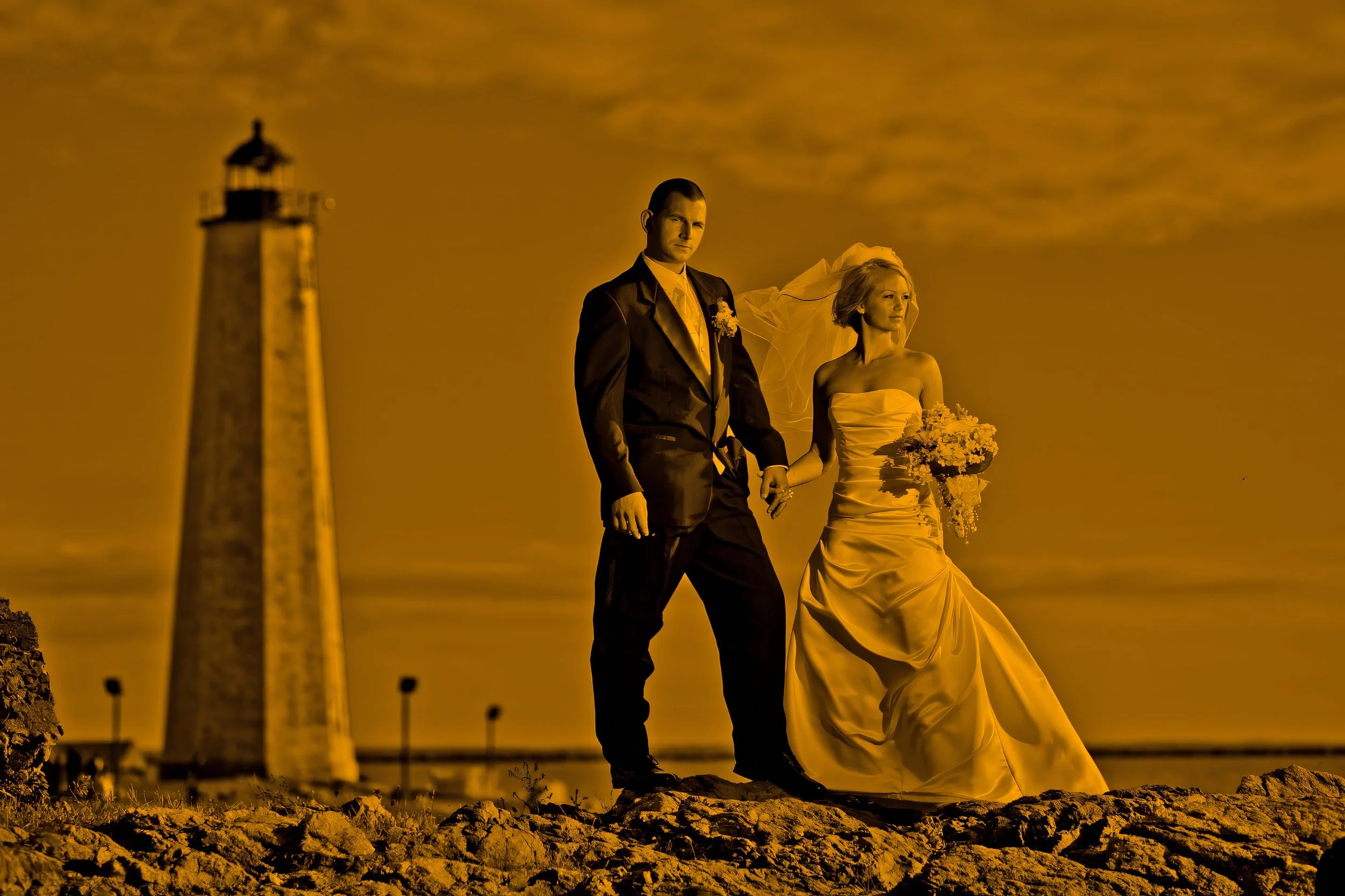 Fine art wedding portrait of bride and groom standing together with Lighthouse Point Park lighthouse in the distance in New Haven Connecticut