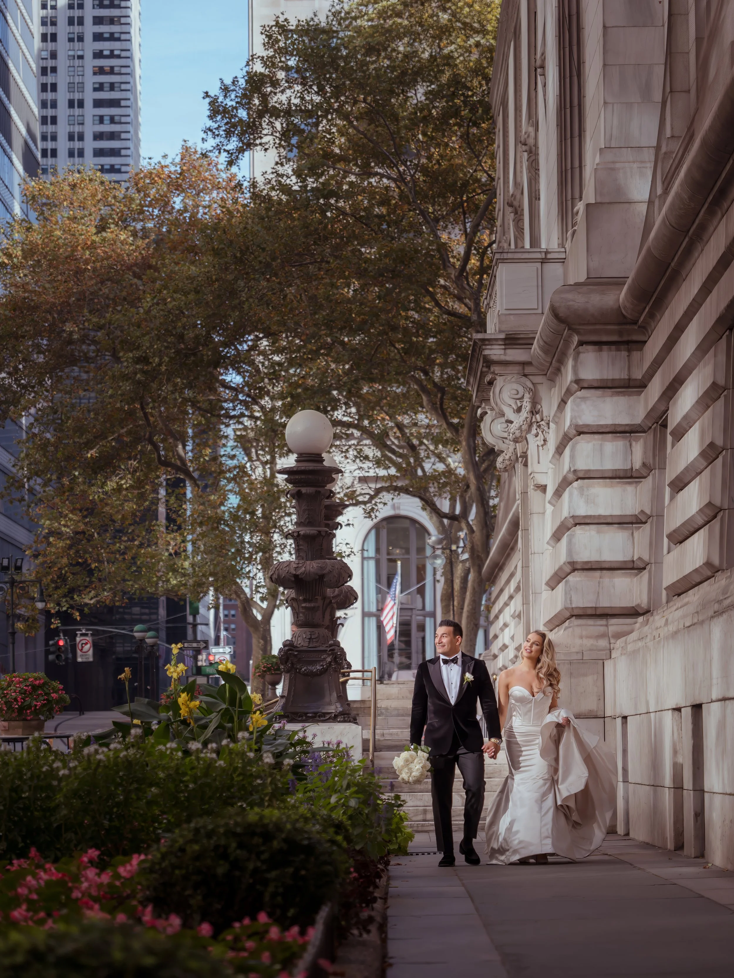 Bride and groom walking toward Bryant Park after portraits at the New York Public Library Midtown Manhattan wedding