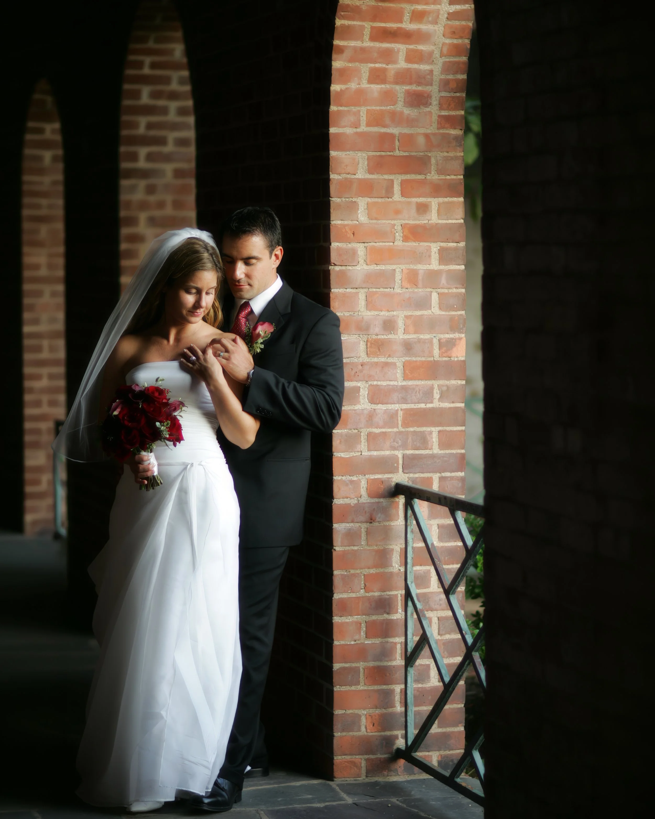 Loving portrait of bride and groom under the brick archways at the New Haven Lawn Club.