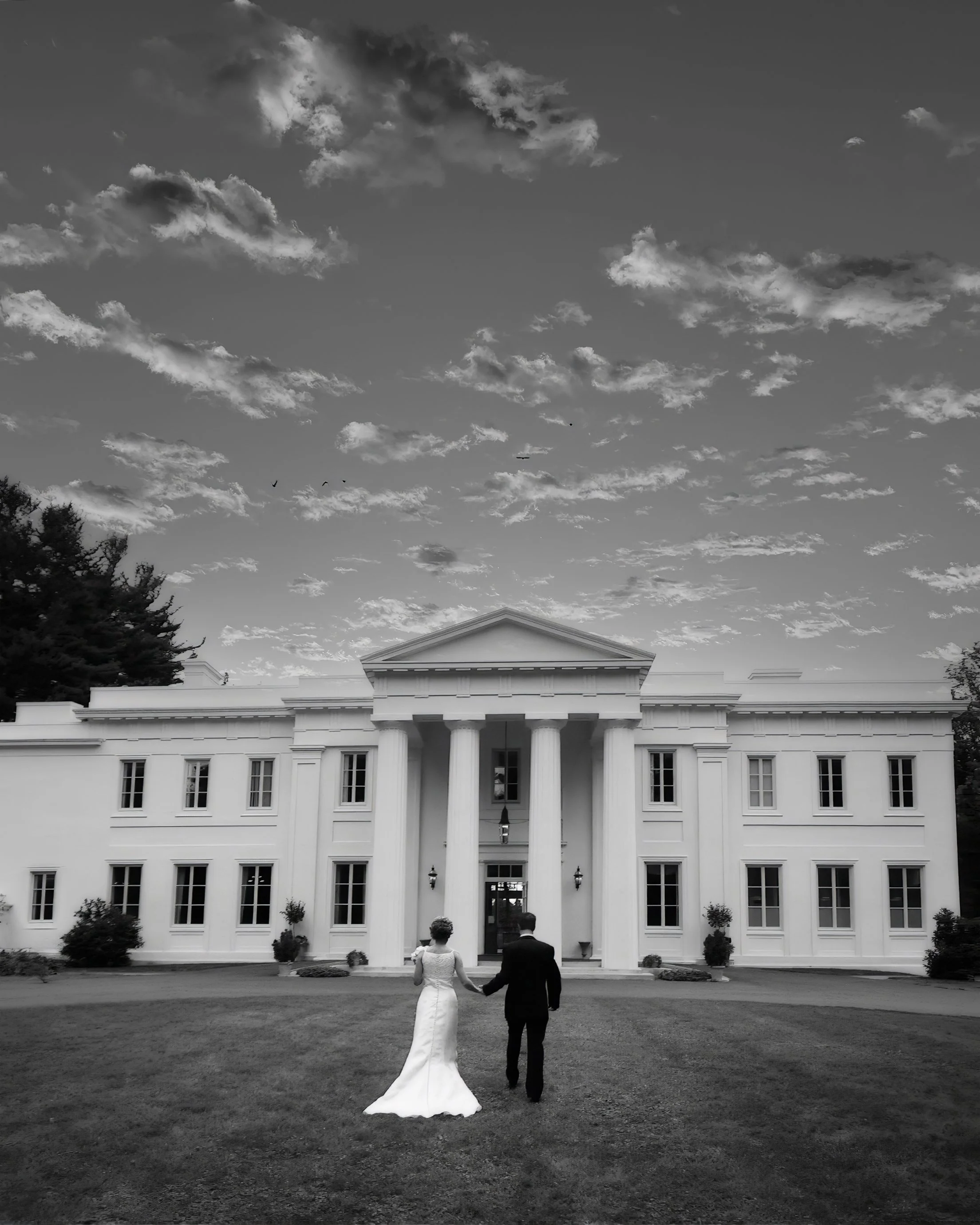 Bride and groom walking hand in hand toward Wadsworth Mansion in Middletown, Connecticut highlighting the scale of the estate.