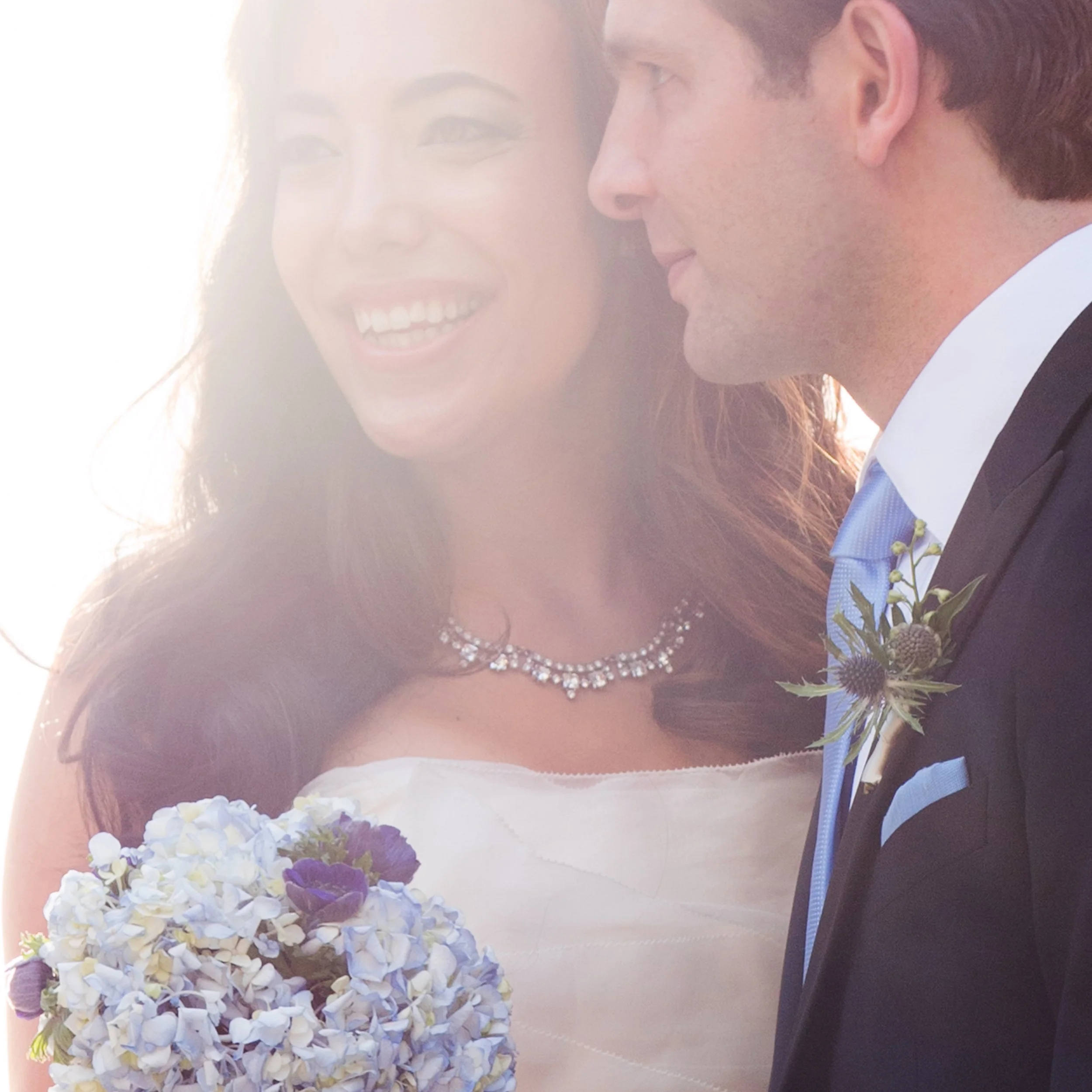 Natural light portrait of a bride and groom standing together in warm afternoon sunshine at Tribeca Rooftop in New York City.