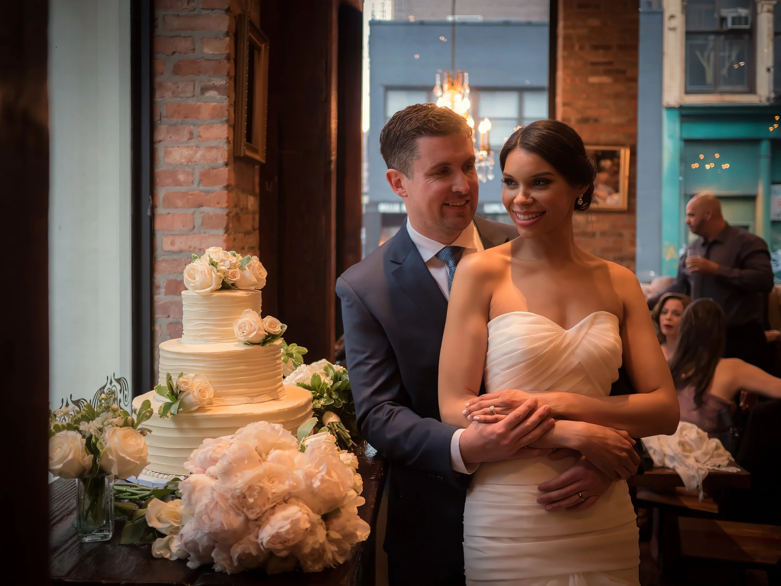 Bride and groom share a romantic moment in window light before cutting their wedding cake at Añejo NYC.