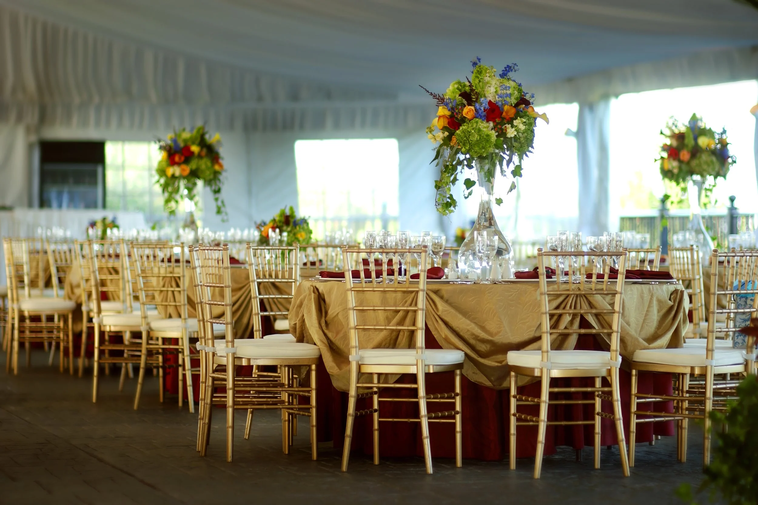 Tented reception at Castle Hill with tables adorned in tall, elegant floral centerpieces.