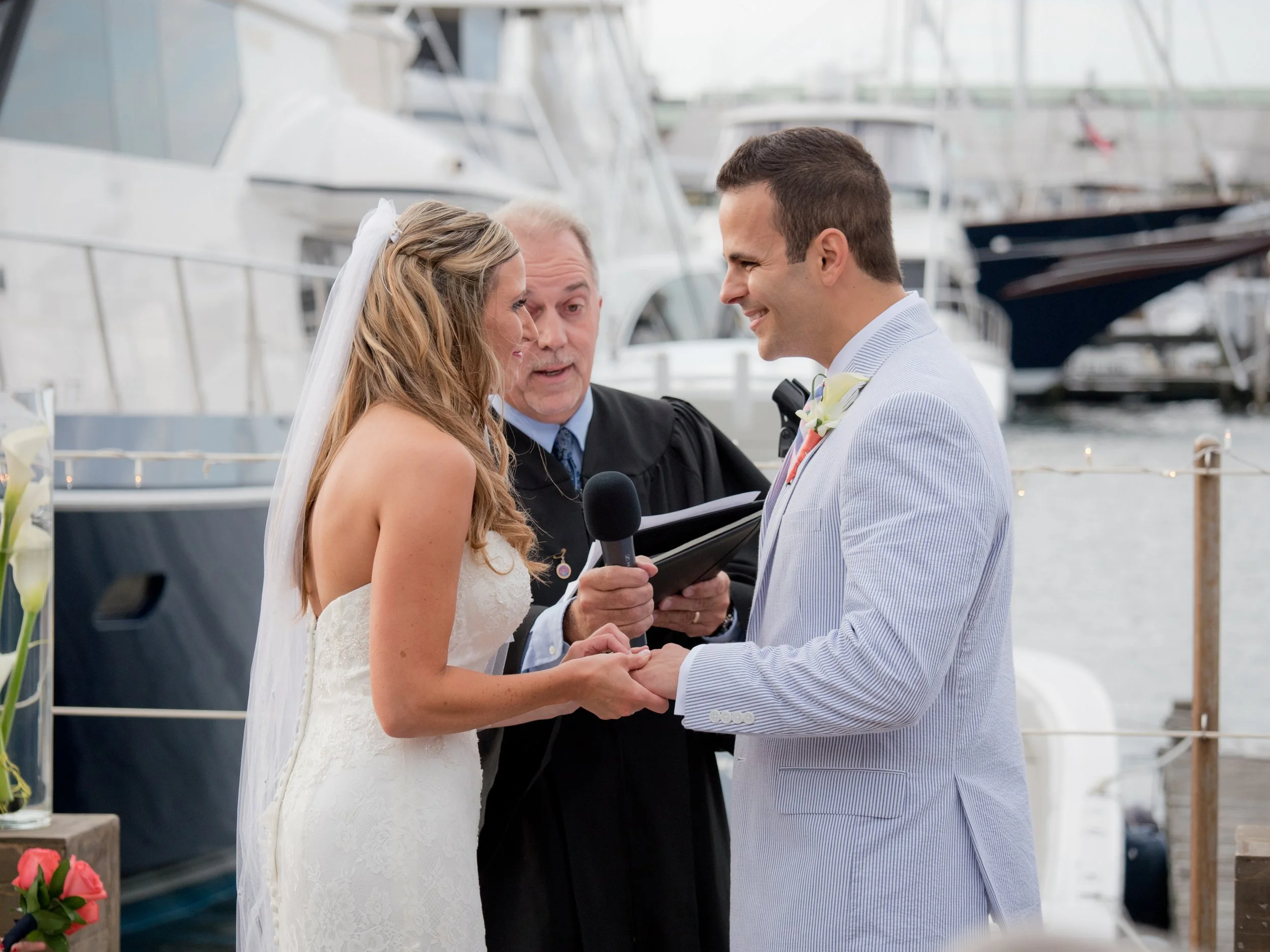 Bride and groom exchange wedding rings during their dockside ceremony at the Newport Yachting Center.