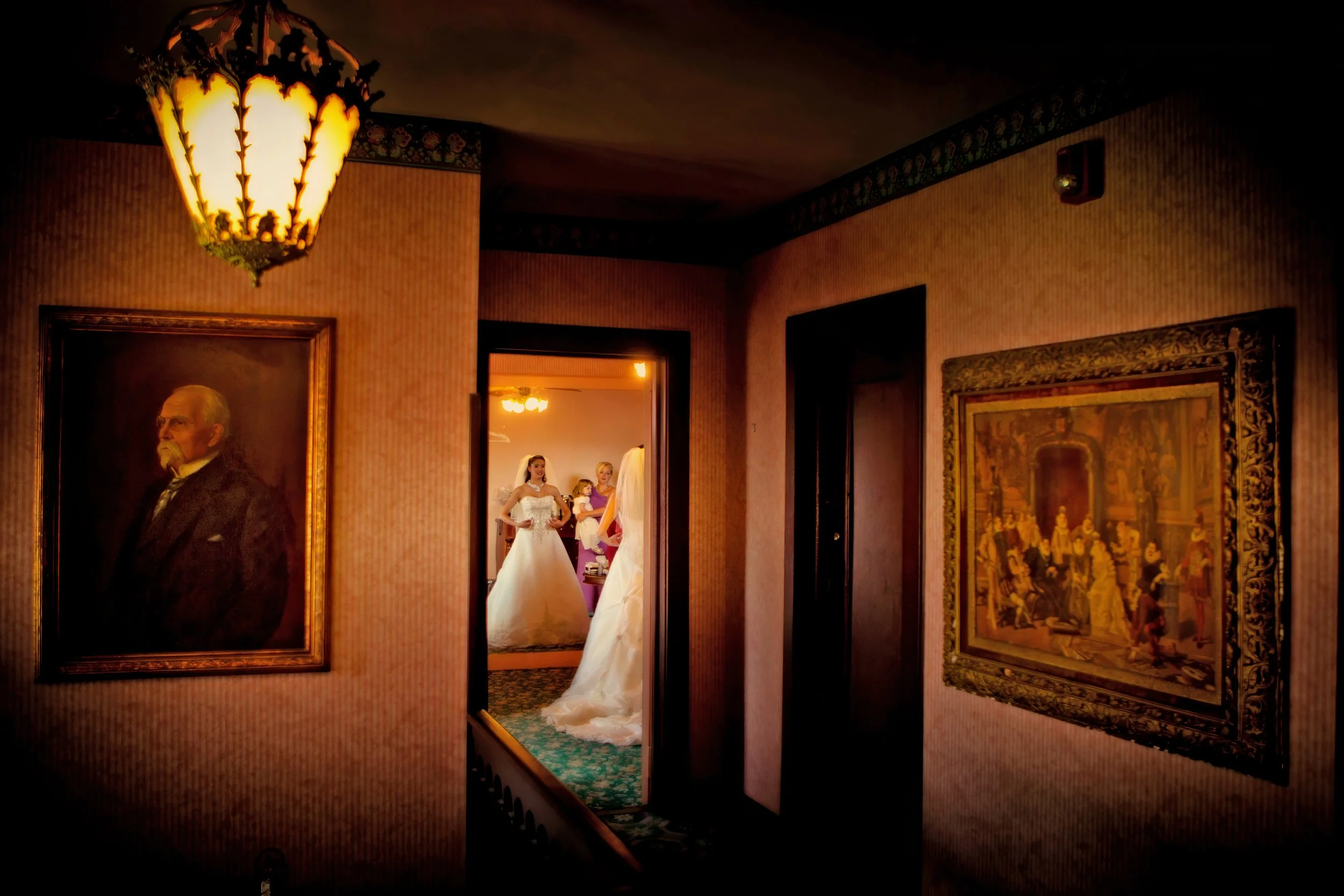 Bride looks at herself in the mirror through the doorway of the bridal suite at Saint Clements Castle.