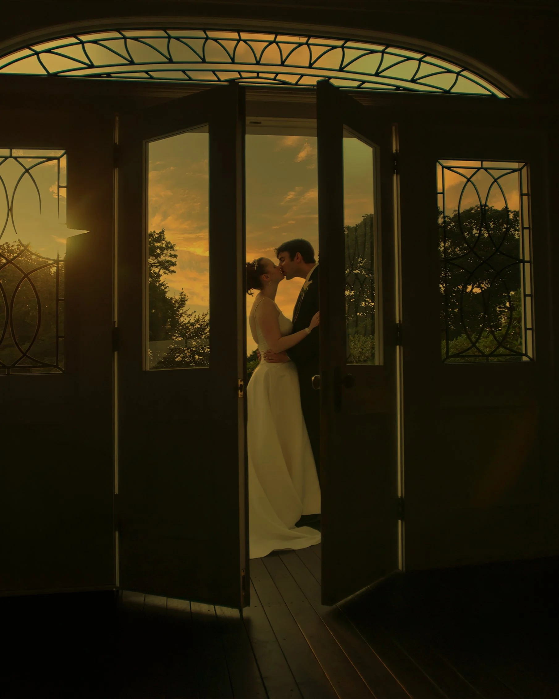 Silhouette of a bride and groom framed in a doorway at the Haley Mansion, bathed in sunlight.