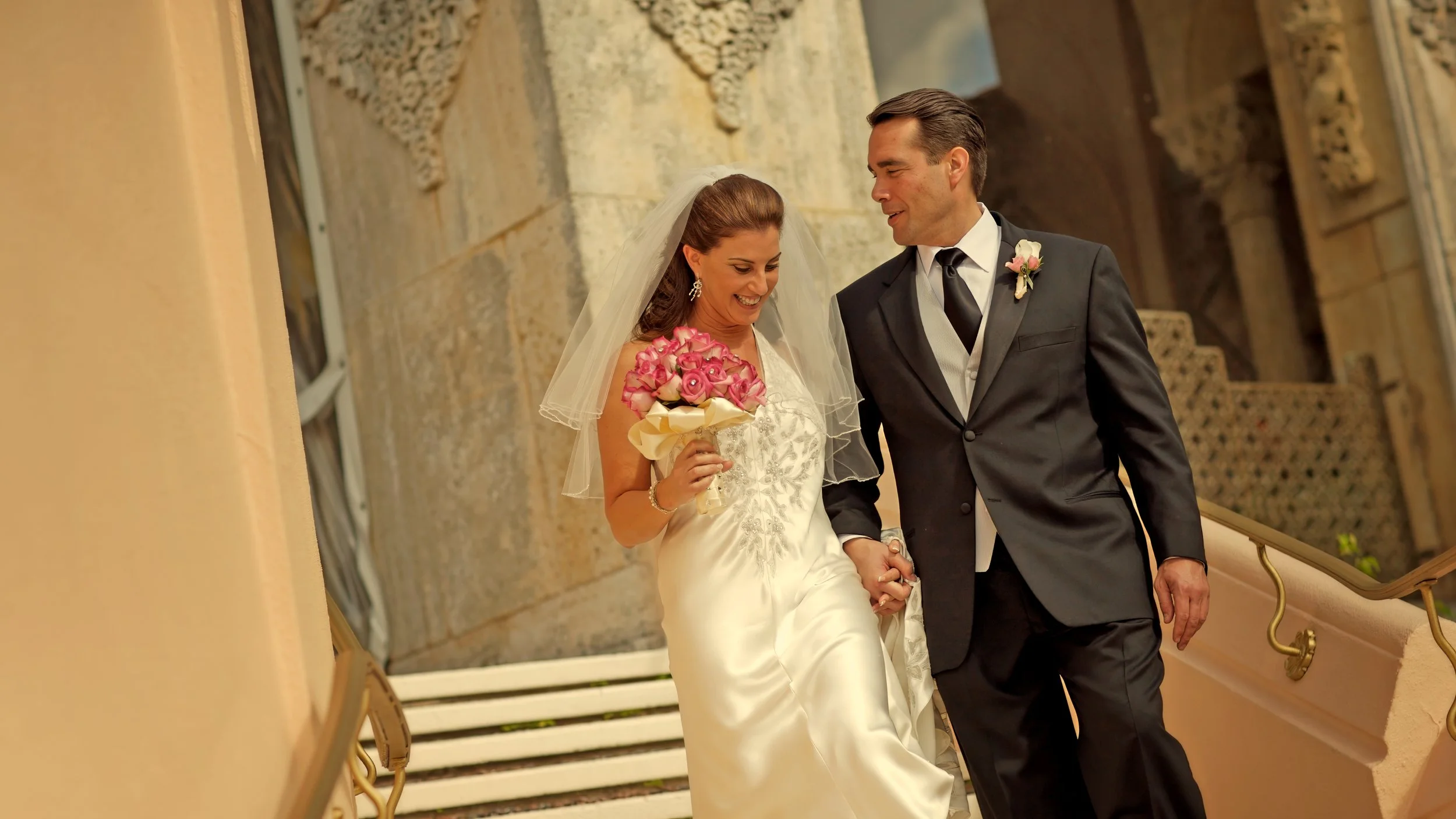 Bride and groom walking hand in hand down the outdoor staircase at Mar-a-Lago in Palm Beach