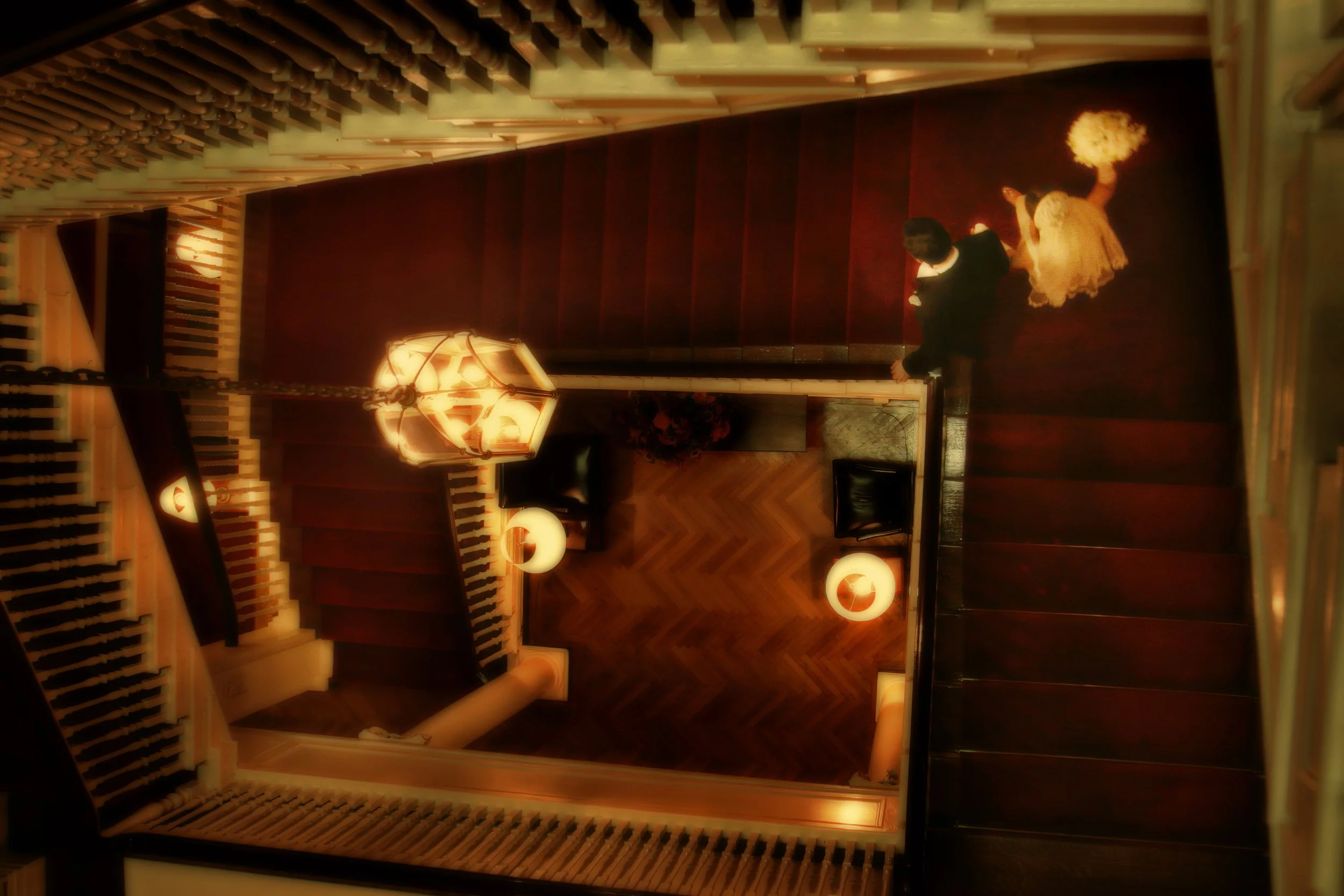 Bride and groom descend the grand staircase at The Harvard Club surrounded by warm ambient light.