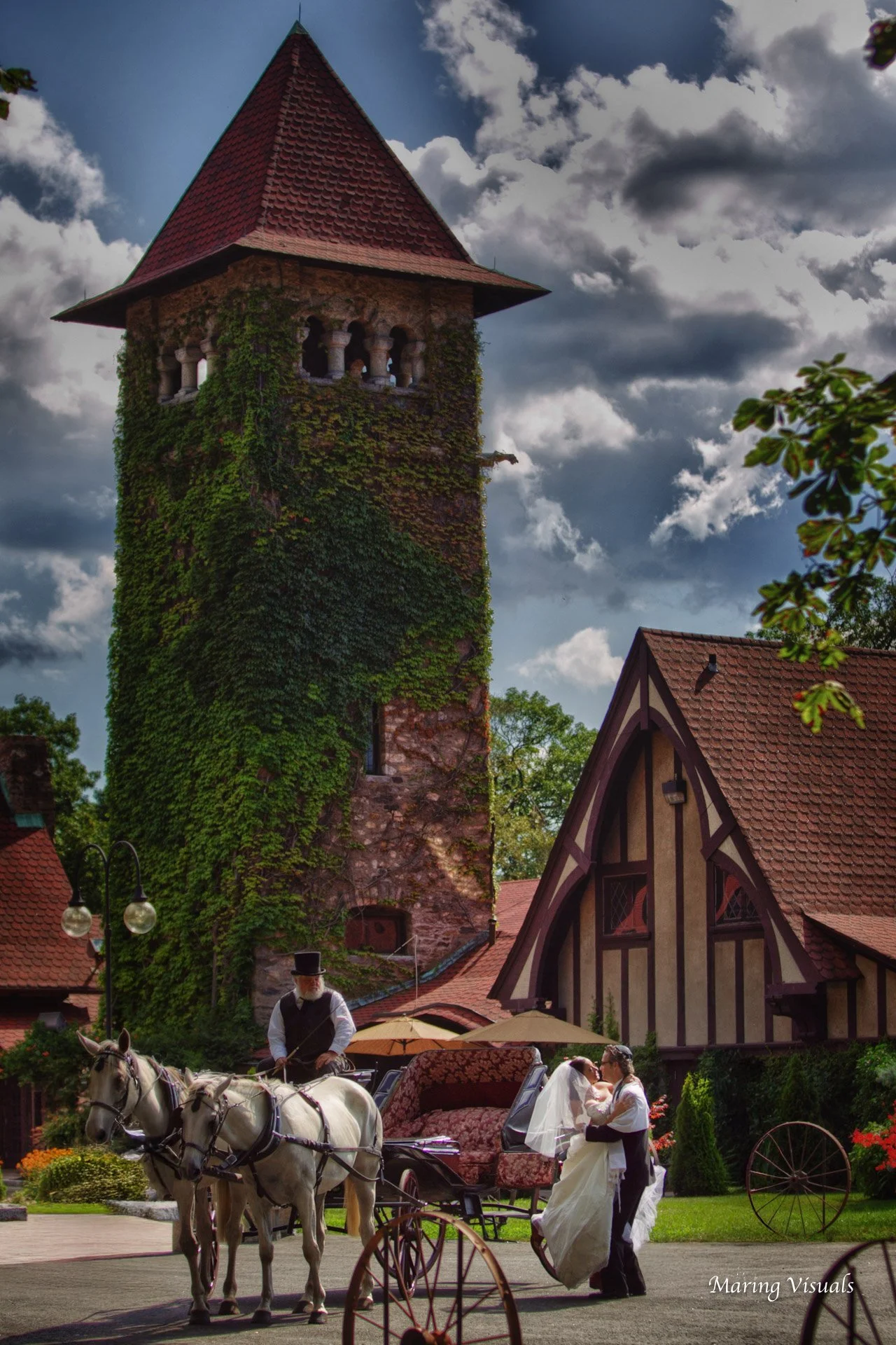 Groom helping the bride step down from a horse drawn carriage beneath the spire of Saint Clements Castle in Portland, Connecticut.