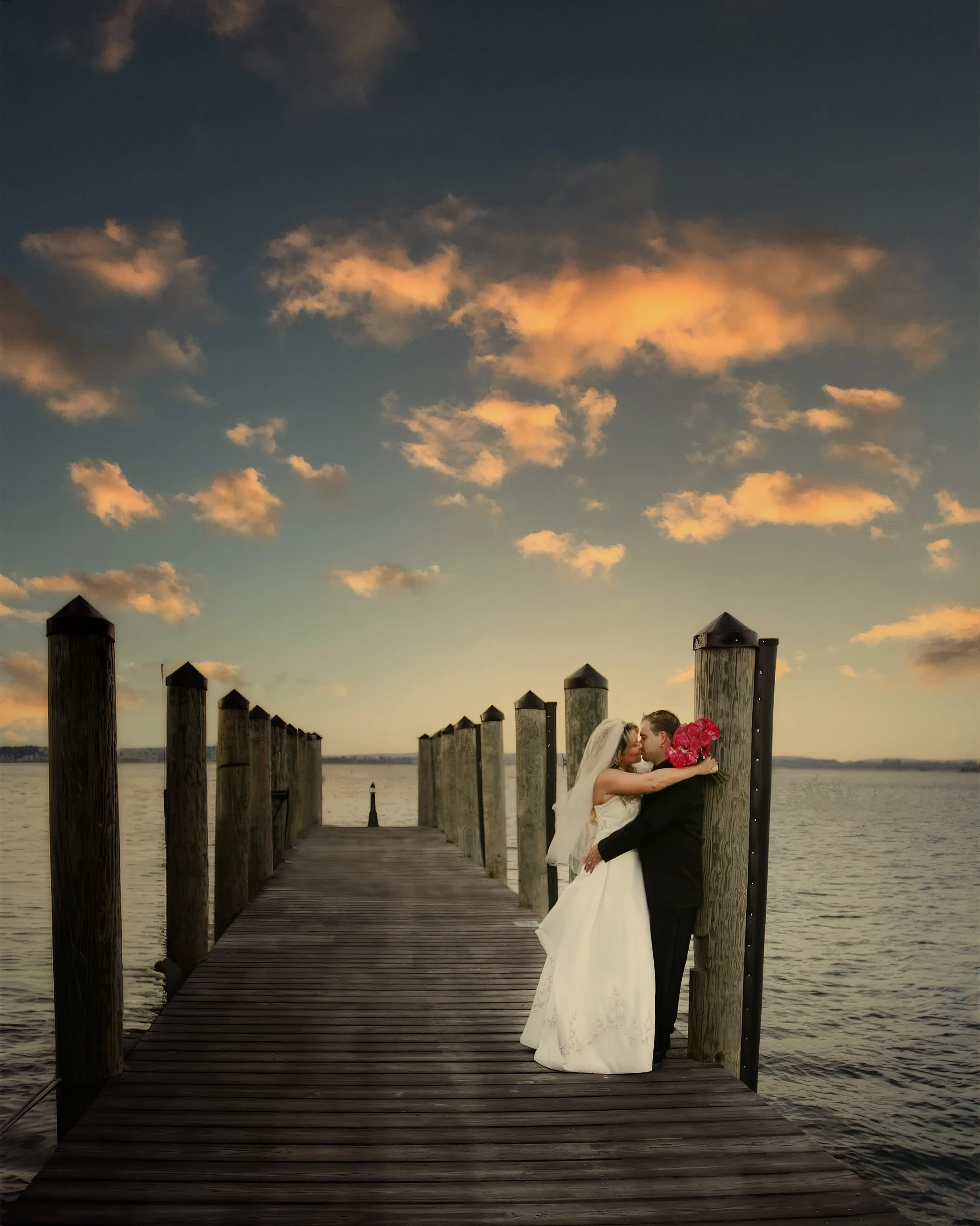 Bride and groom kissing on the docks at Saybrook Point Resort & Marina in Old Saybrook, Connecticut beneath a soft evening sky.