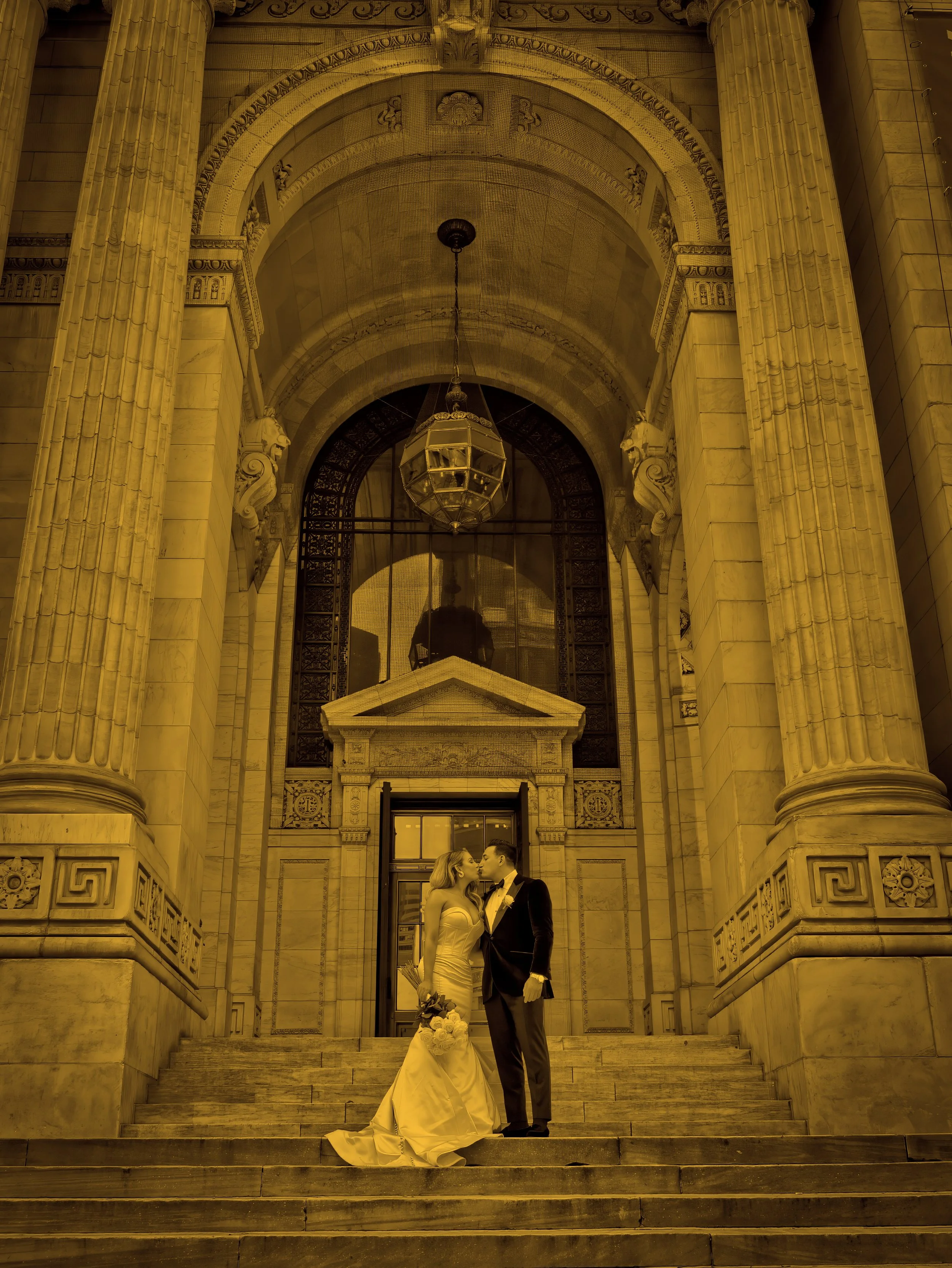 Fine art photograph of bride and groom kissing beneath arches on the steps of the New York Public Library wedding NYC