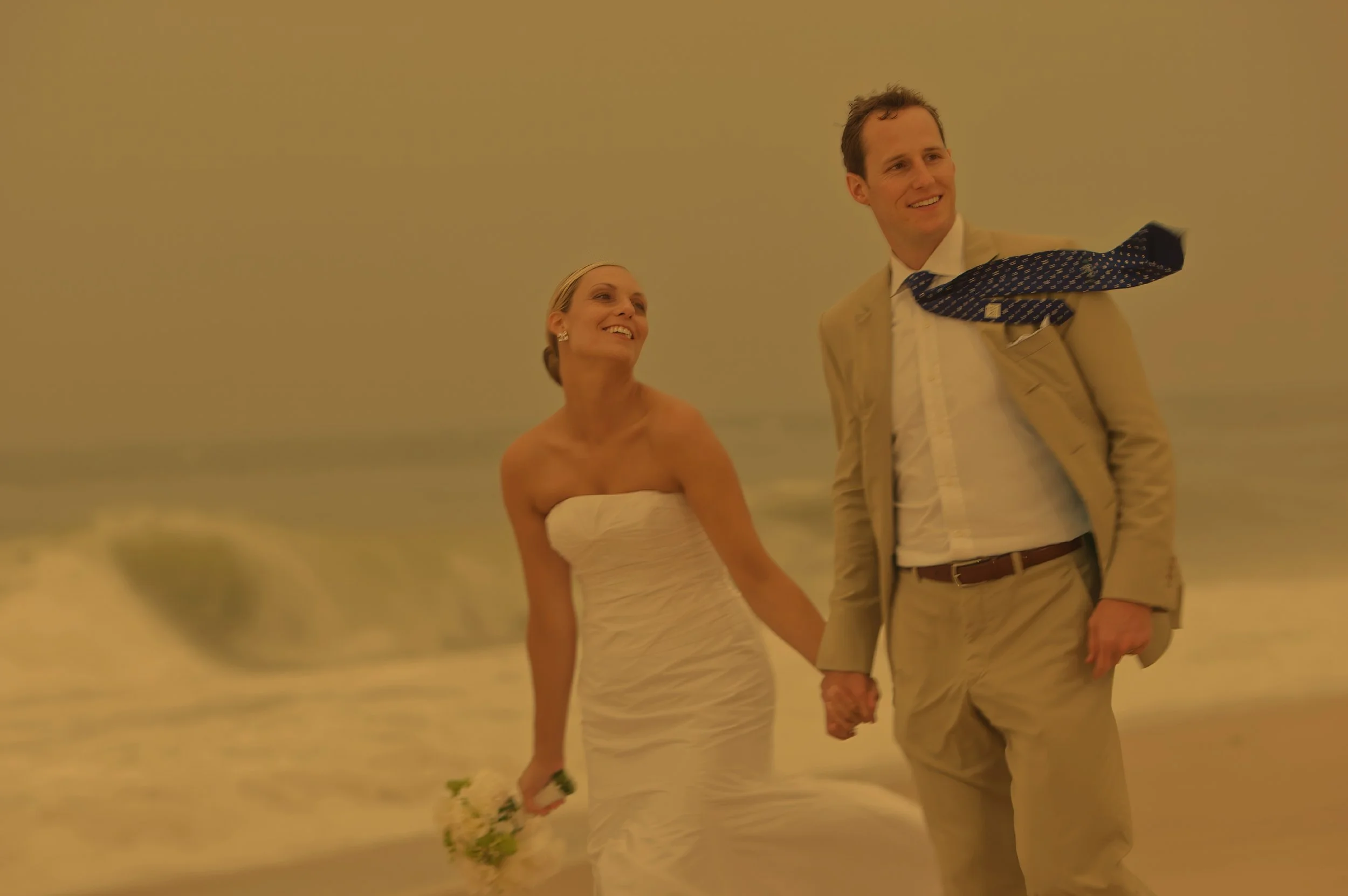 Wind and waves as the bride and groom walk on the beach at Bridgehampton Tennis and Surf Club