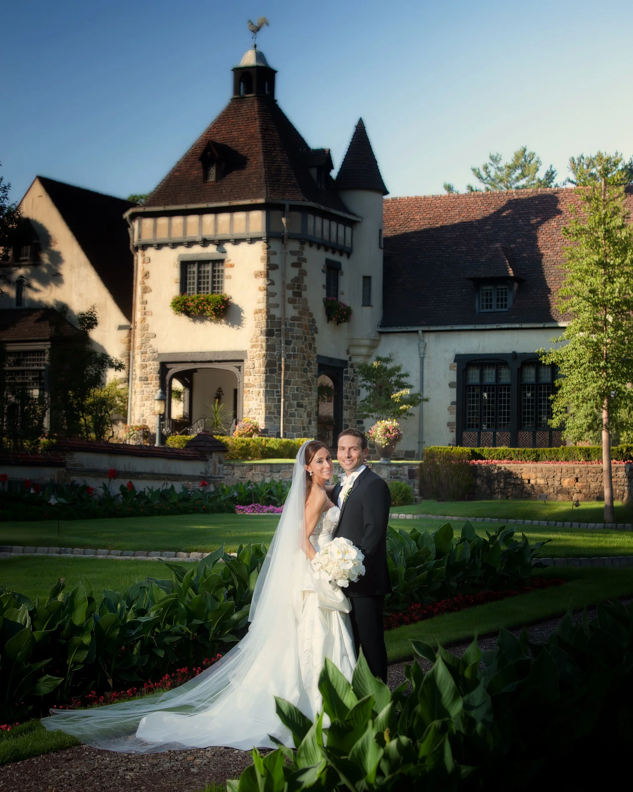 Bride and groom pose for a classic portrait beneath the grand architecture of Pleasantdale Chateau Mansion.