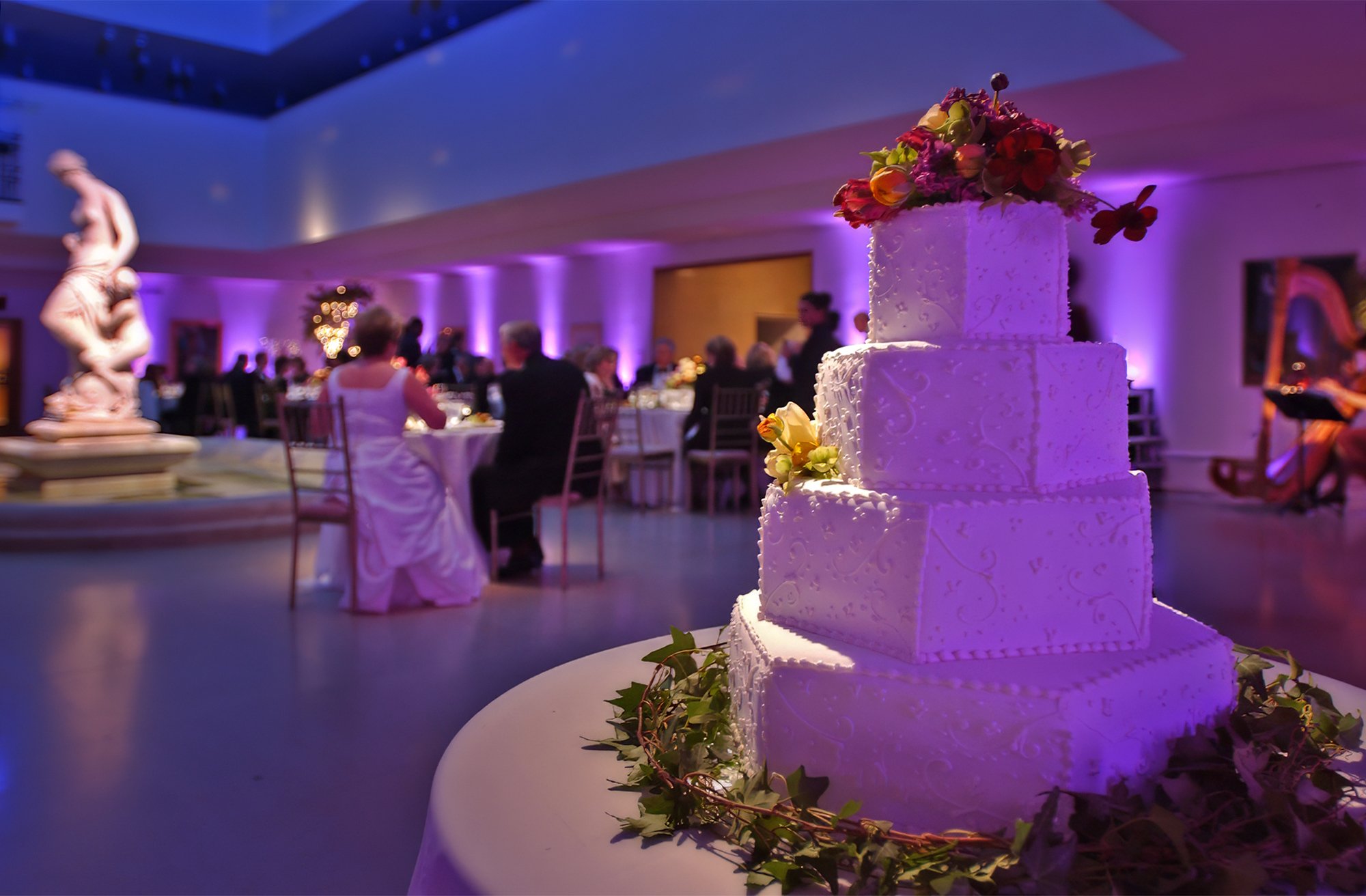 Bride and groom dining during their wedding reception as a harpist performs at the Wadsworth Atheneum.