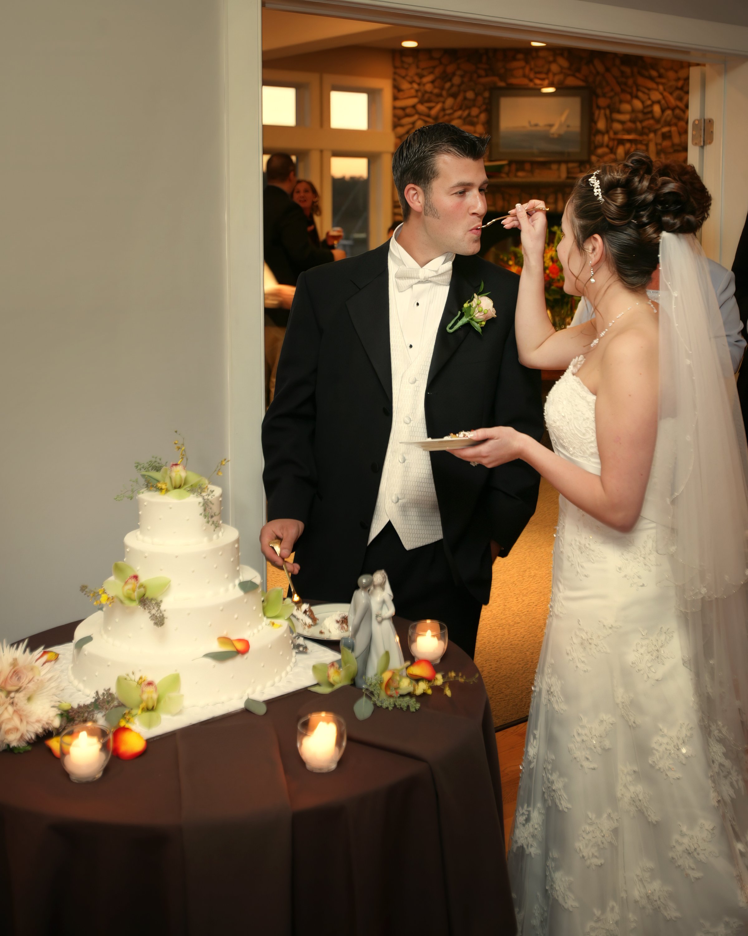 Bride feeds the groom wedding cake during their reception at Guilford Yacht Club.