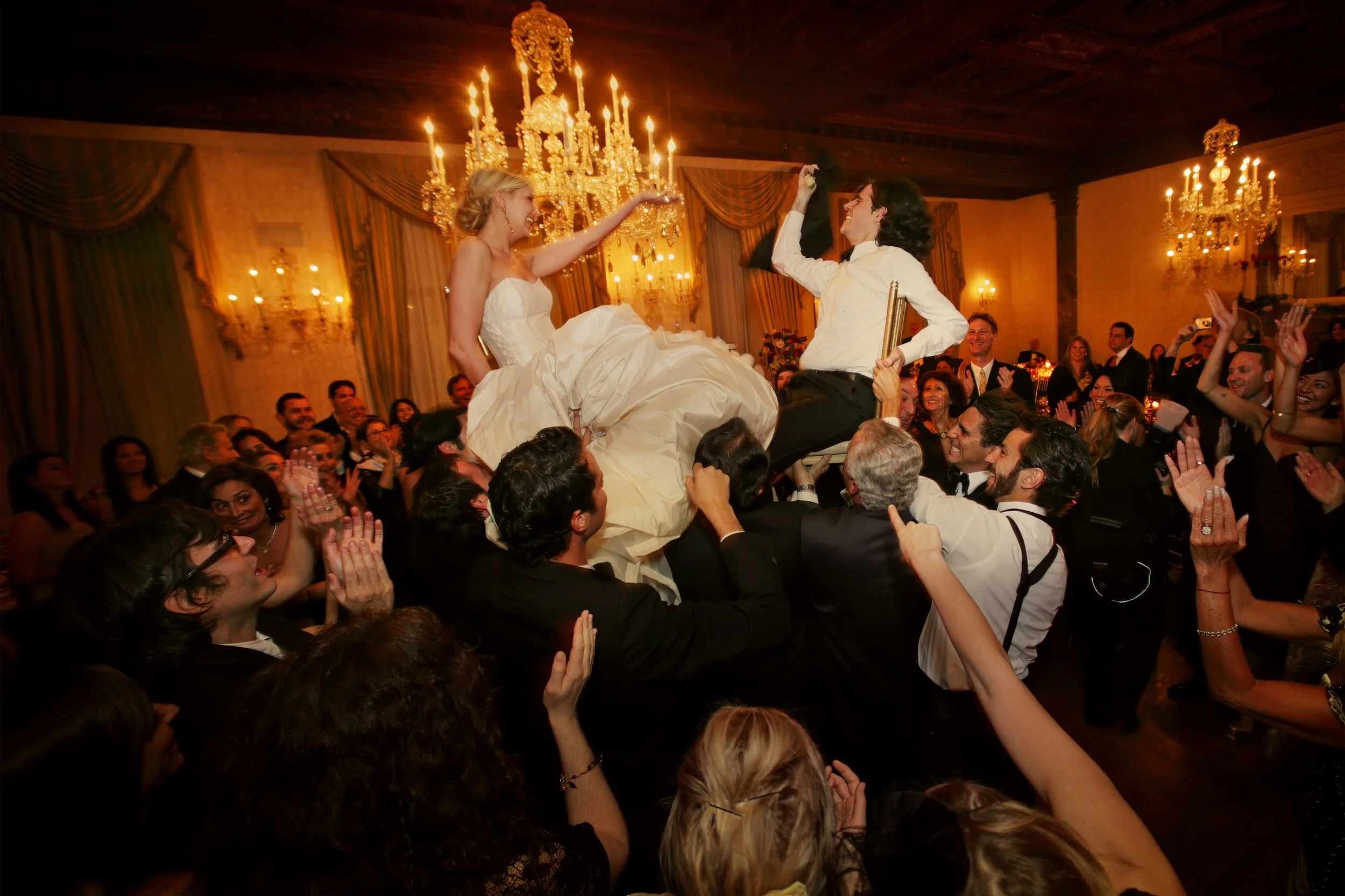 Bride and groom lifted on chairs during celebration at Harmonie Club luxury wedding NYC