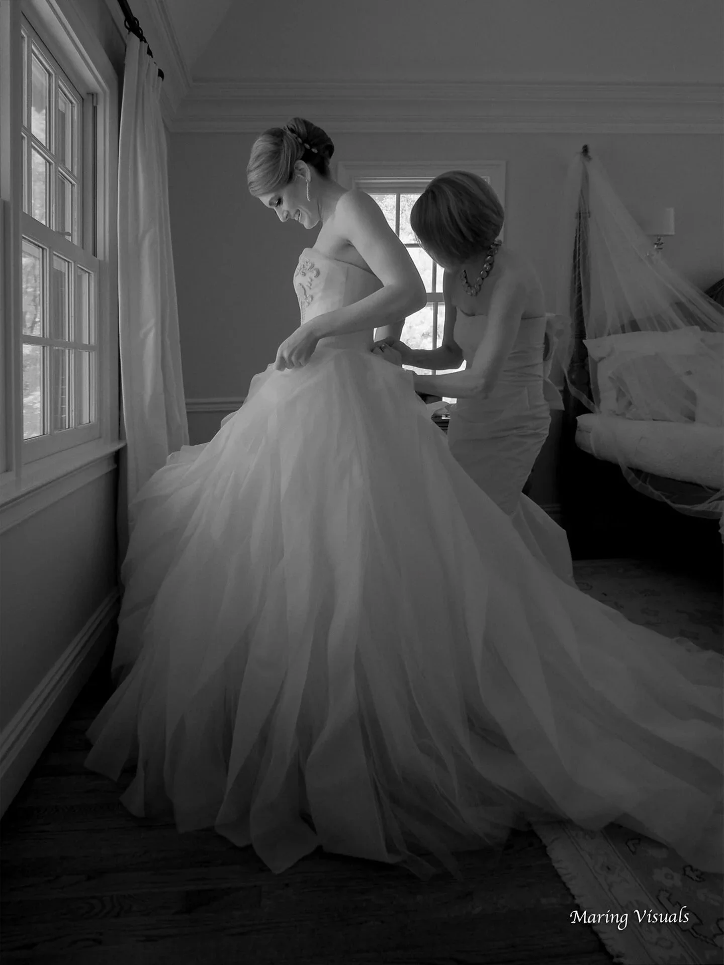 Mother of the bride helping her daughter into her wedding dress at their family home in Westchester County, NY, captured in ethereal black and white.