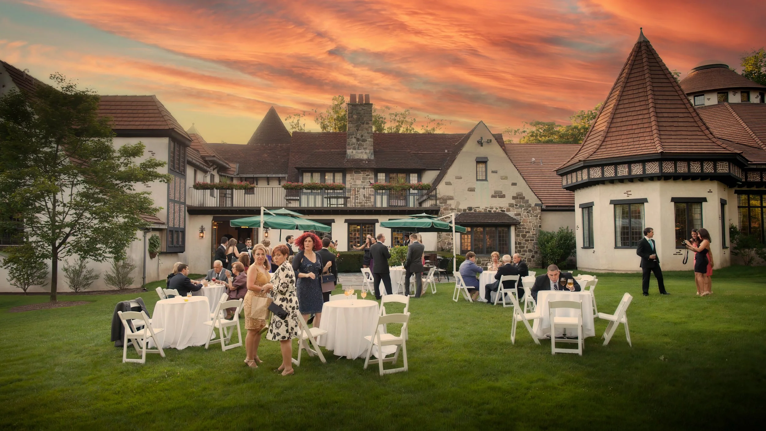 Wedding guests mingle outdoors during cocktail hour at sunset on the grounds of Pleasantdale Chateau.