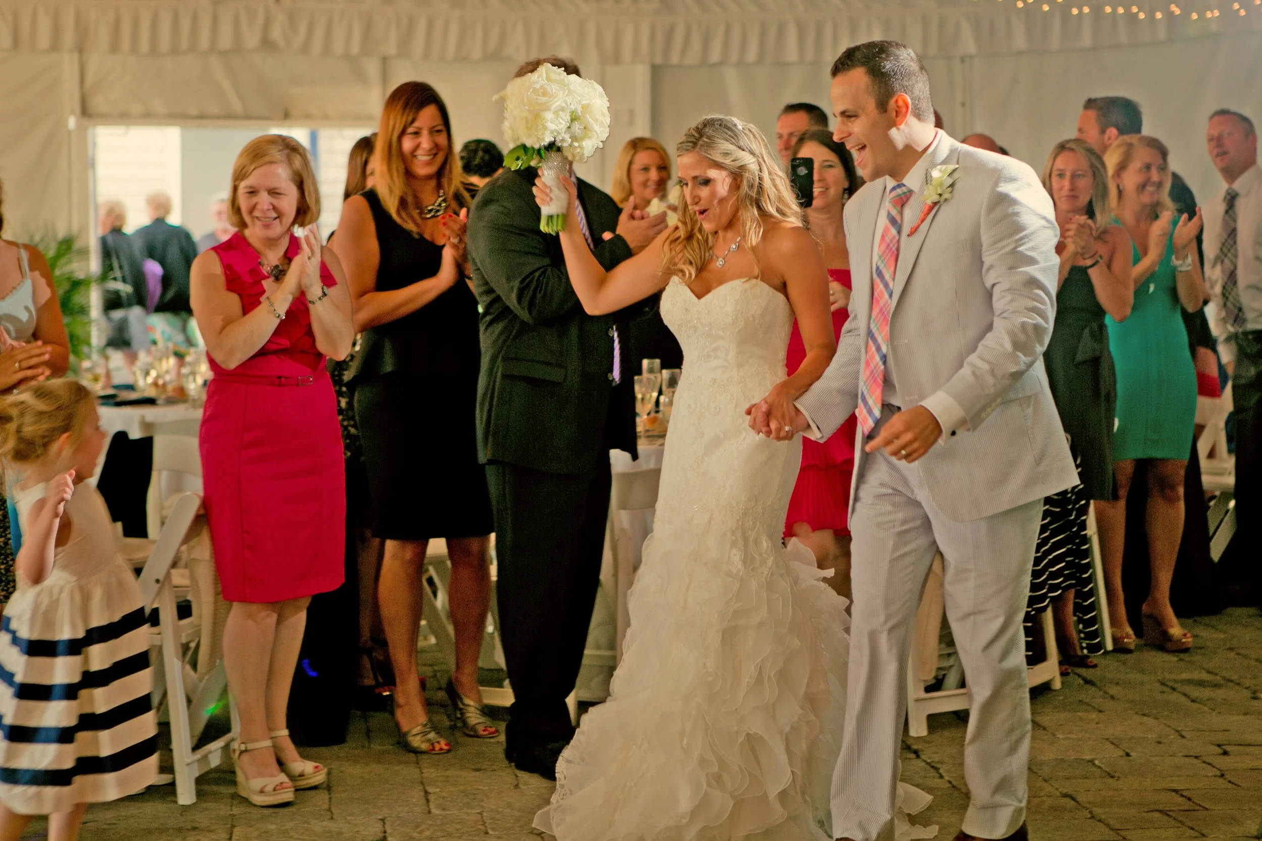 Bride and groom make a joyful grand entrance to their tented wedding reception at Newport Yachting Center.