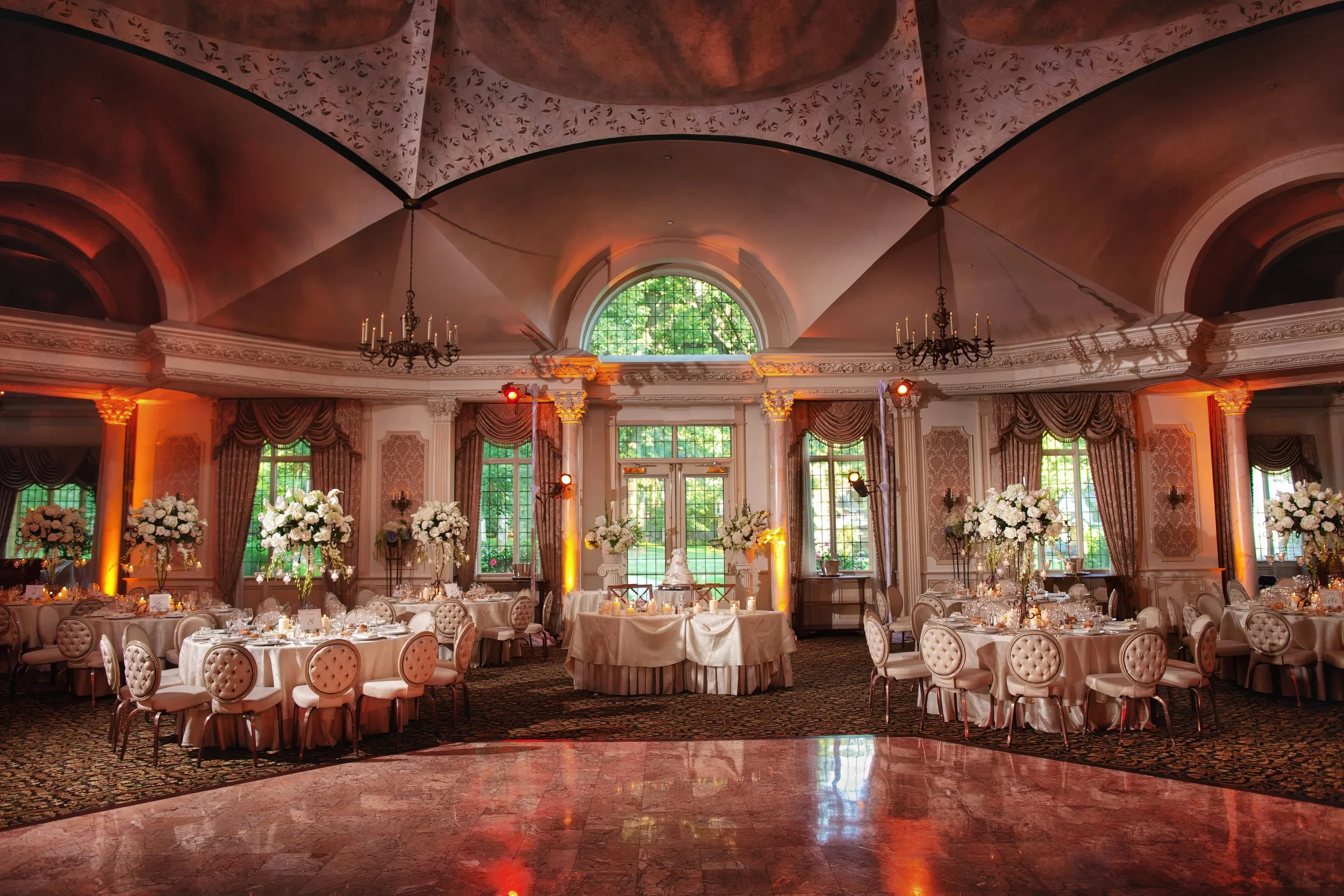 Rotunda ballroom at Pleasantdale Chateau decorated for a wedding reception with tables and floral arrangements.