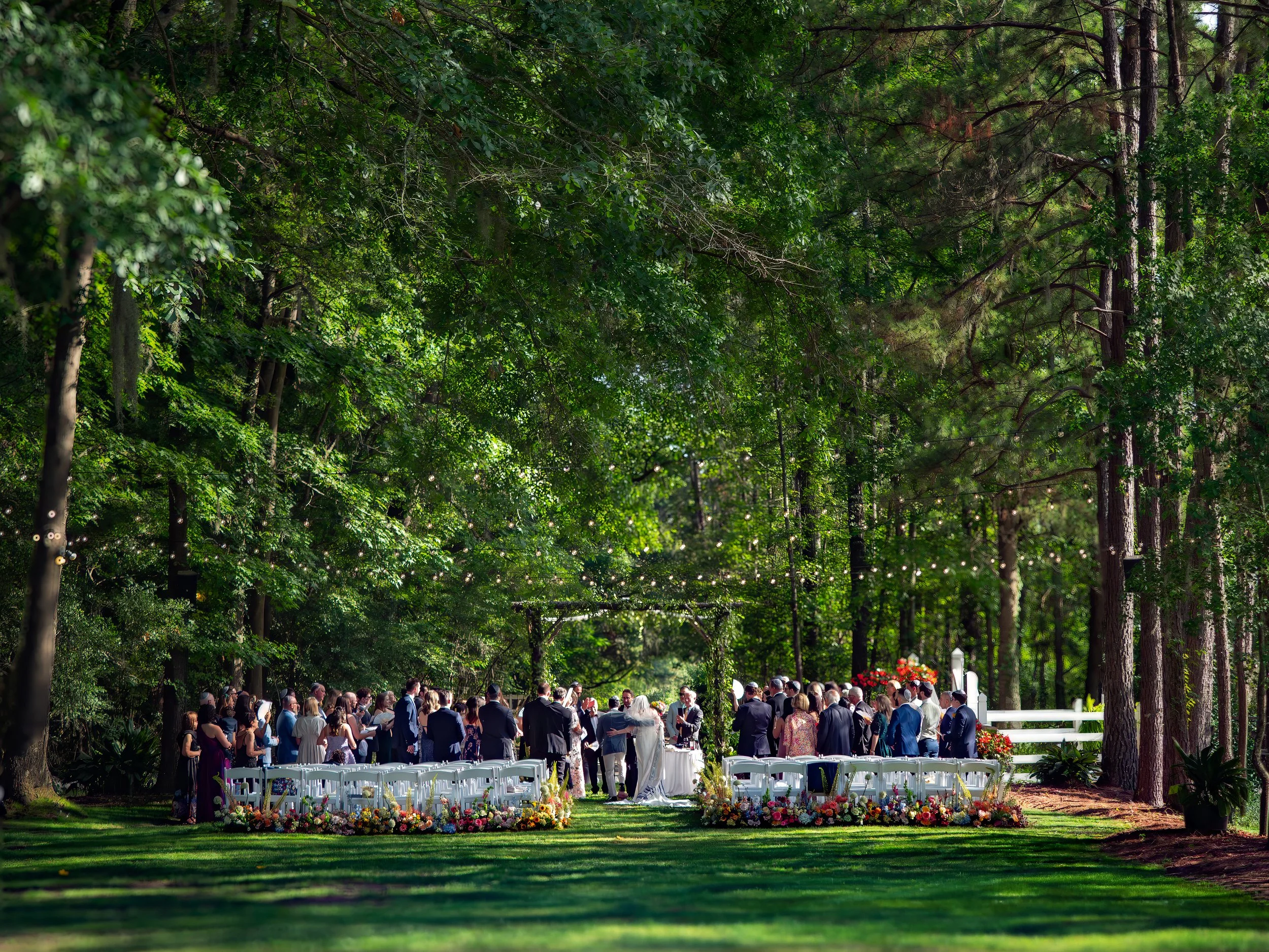 Wide view of an outdoor wedding ceremony beneath mature trees at The Mackey House wedding venue near Savannah, Georgia.