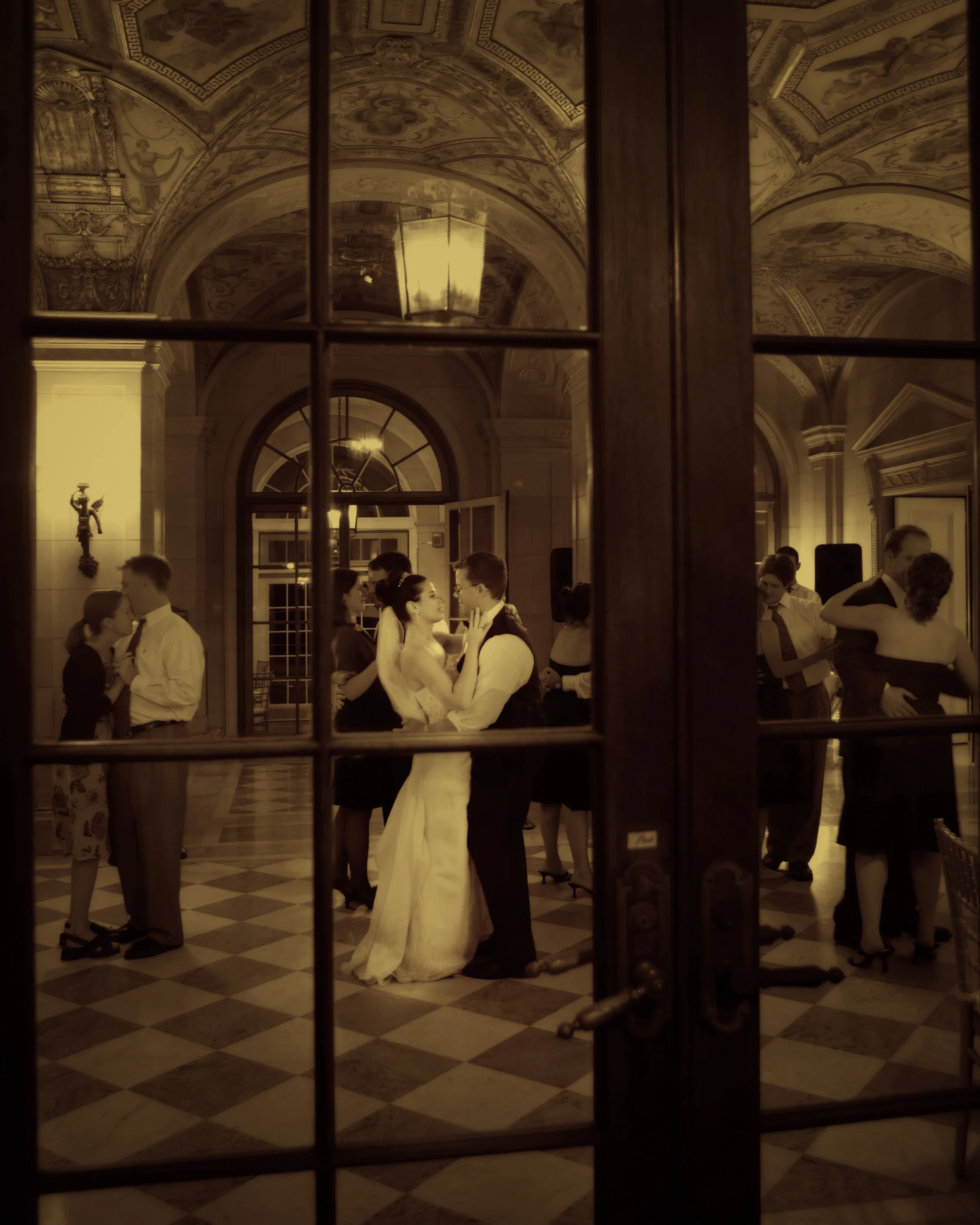 Bride and groom first dance framed through glass doorway panes at Aldrich Mansion reception.