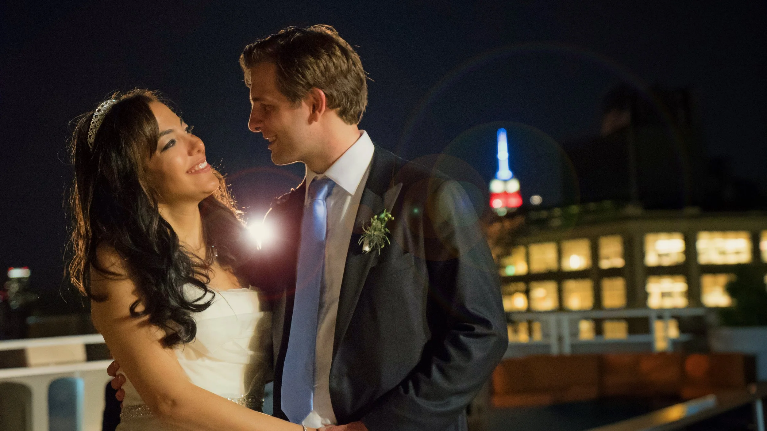 Bride and groom sharing a quiet moment together at night atop Tribeca Rooftop with the Manhattan skyline glowing in the distance.
